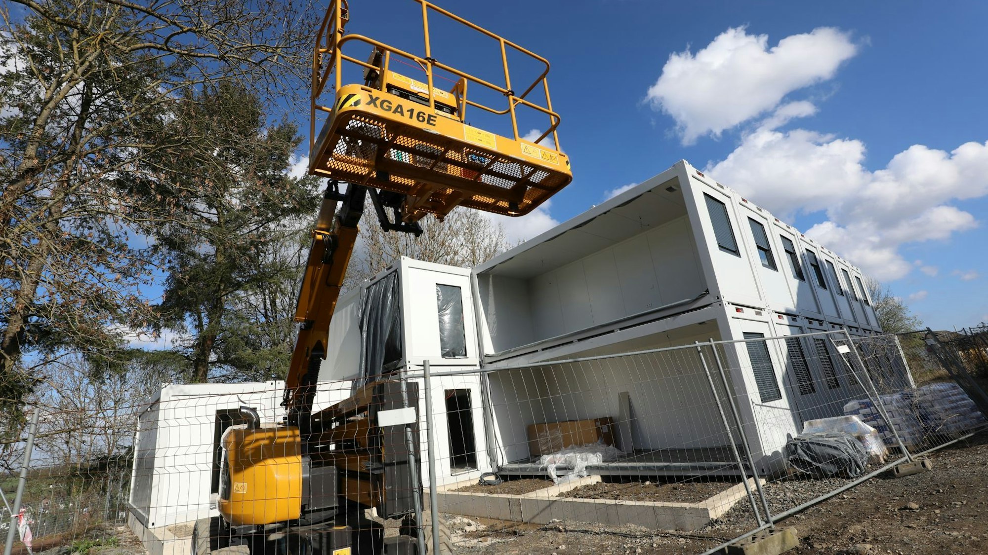 Eine Baufahrzeug mit Hebebühne neben Wohncontainern.
