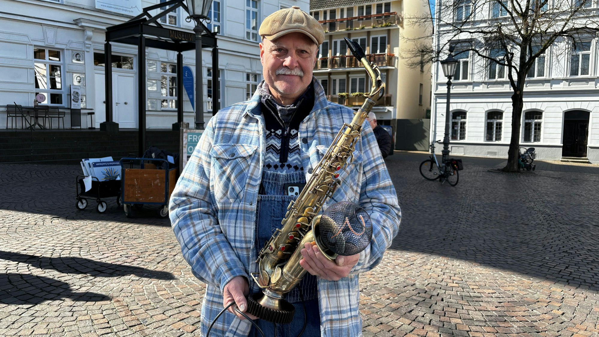 Ein Mann hält eine Lampe in Form eines Saxofons in den Händen.