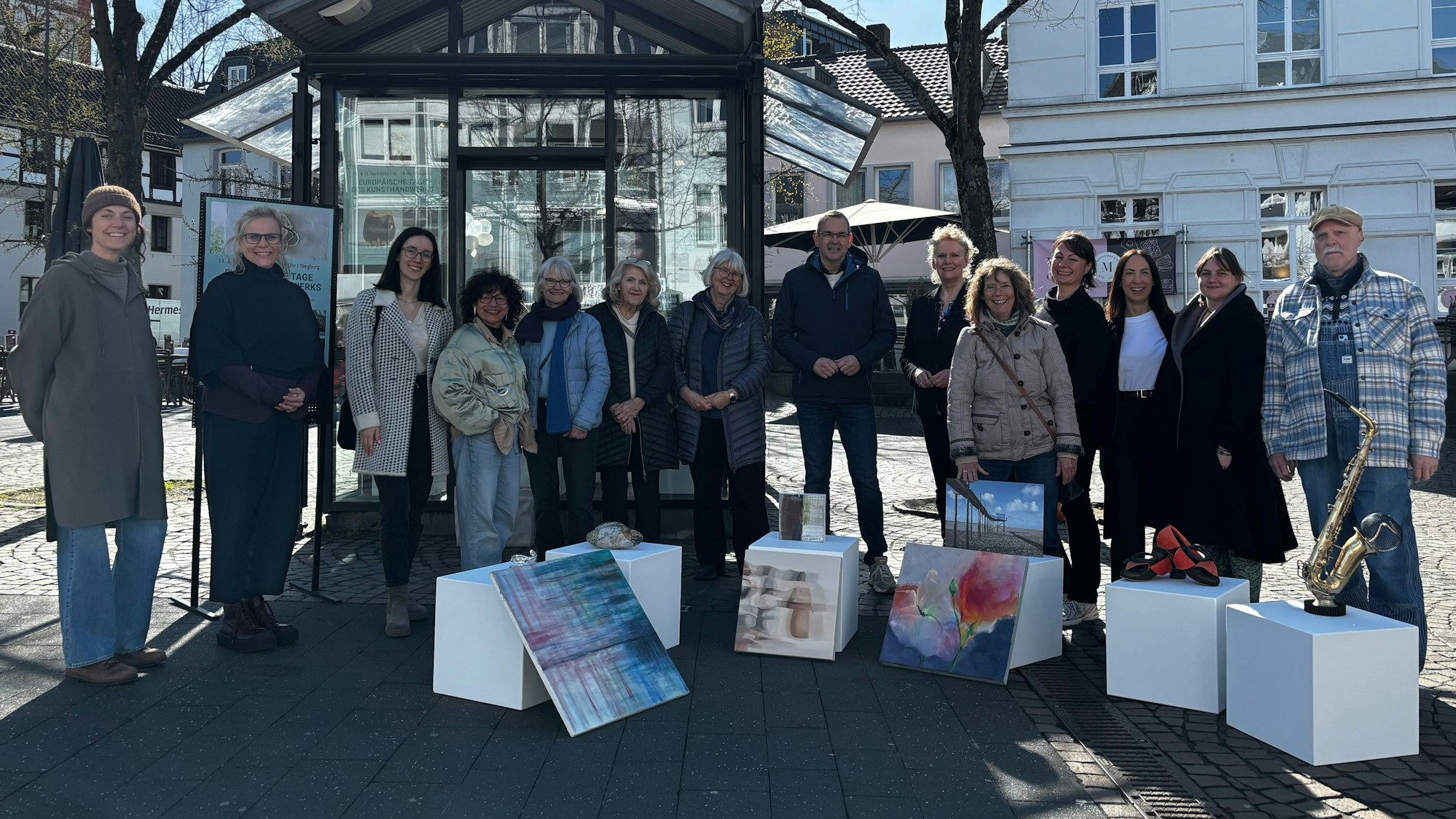 Männer und Frauen stehen auf dem Siegburger Marktplatz vor dem Kultur-Kiosk.