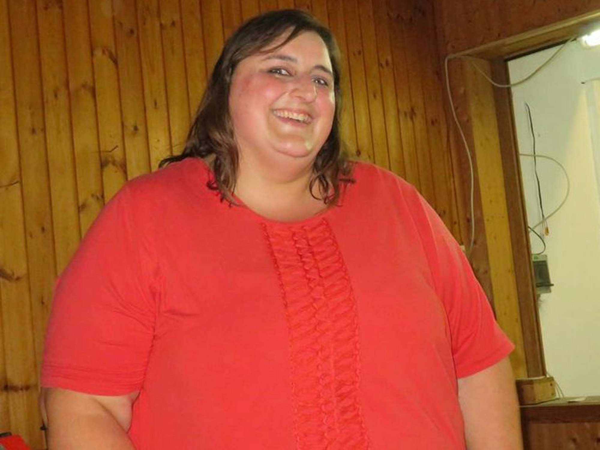 Eine Frau in einem roten T-Shirt lächelt.