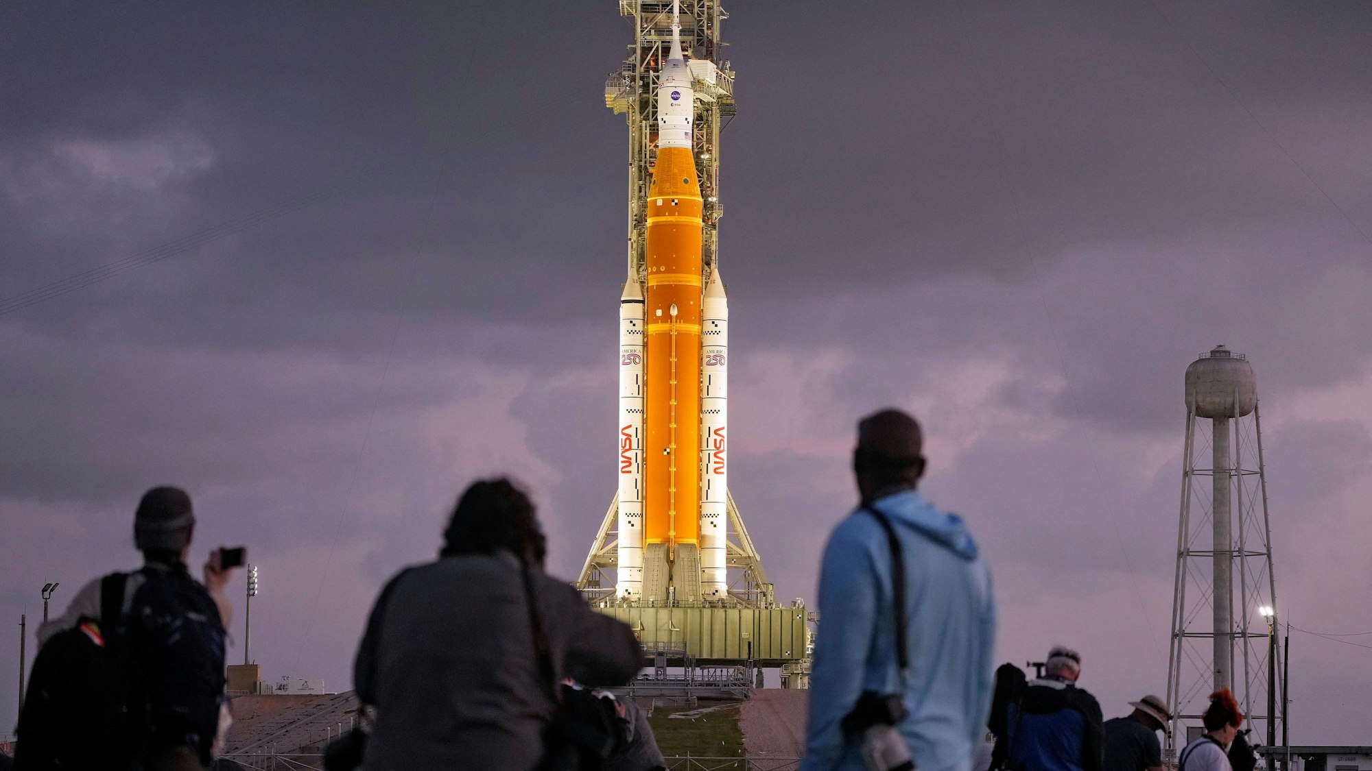 Fotografen richten ferngesteuerte Kameras in der Nähe der Artemis II-Mondrakete der NASA auf der Startrampe 39-B kurz vor Sonnenaufgang im Kennedy Space Center in Cape Canaveral, Florida, ein.