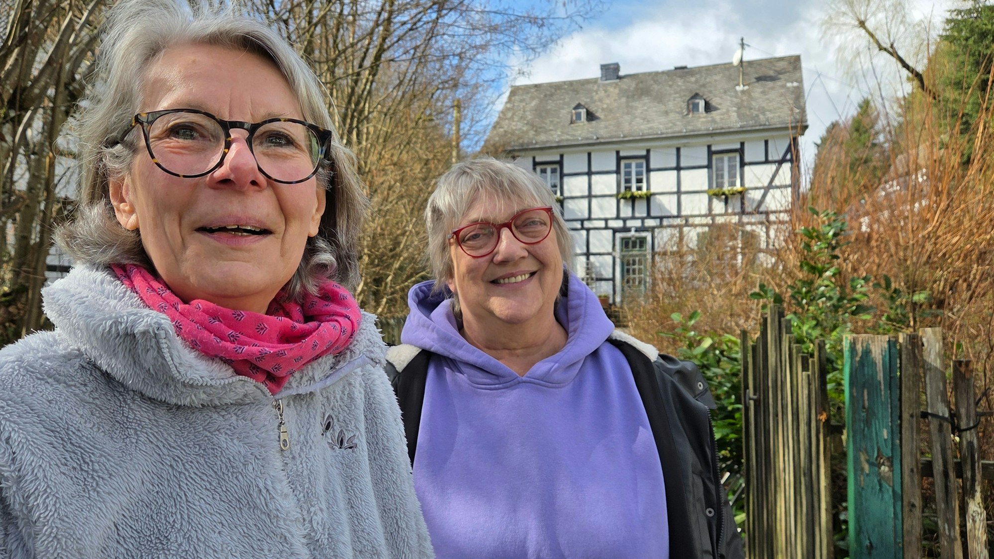 Der Heimatverein von Morsbach-Holpe hat einen Geschichtslehrpfad durch den kleinen Ort eingerichtet. Die Autorin Jutta Ramackers (links) und Sabine Stamp-Eschrig (Vorsitzende des Heimatvereins) stehen dort vor dem historischen Pfarrhaus.
