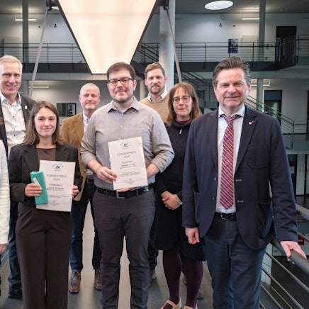 Zwei junge Leute mit Urkunden in einer Gruppe.