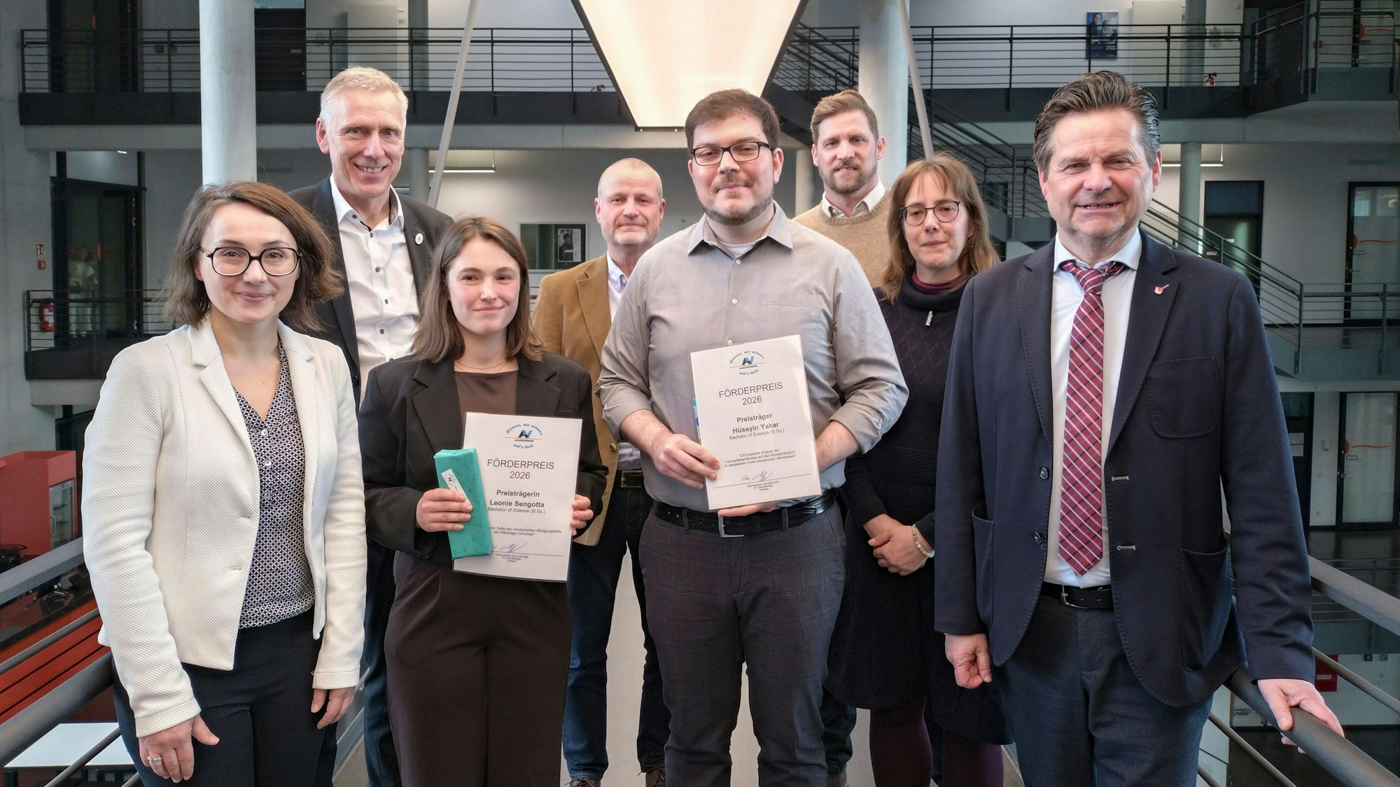 Zwei junge Leute mit Urkunden in einer Gruppe.