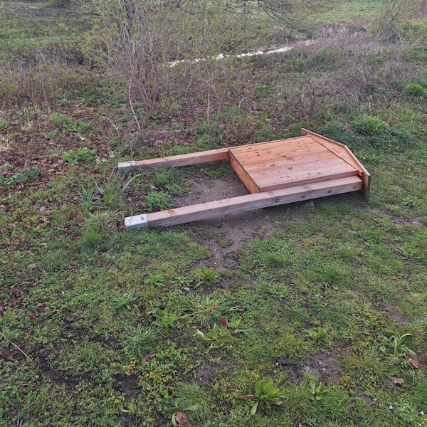 Ein Wildbienenhotel liegt auf einer Wiese.