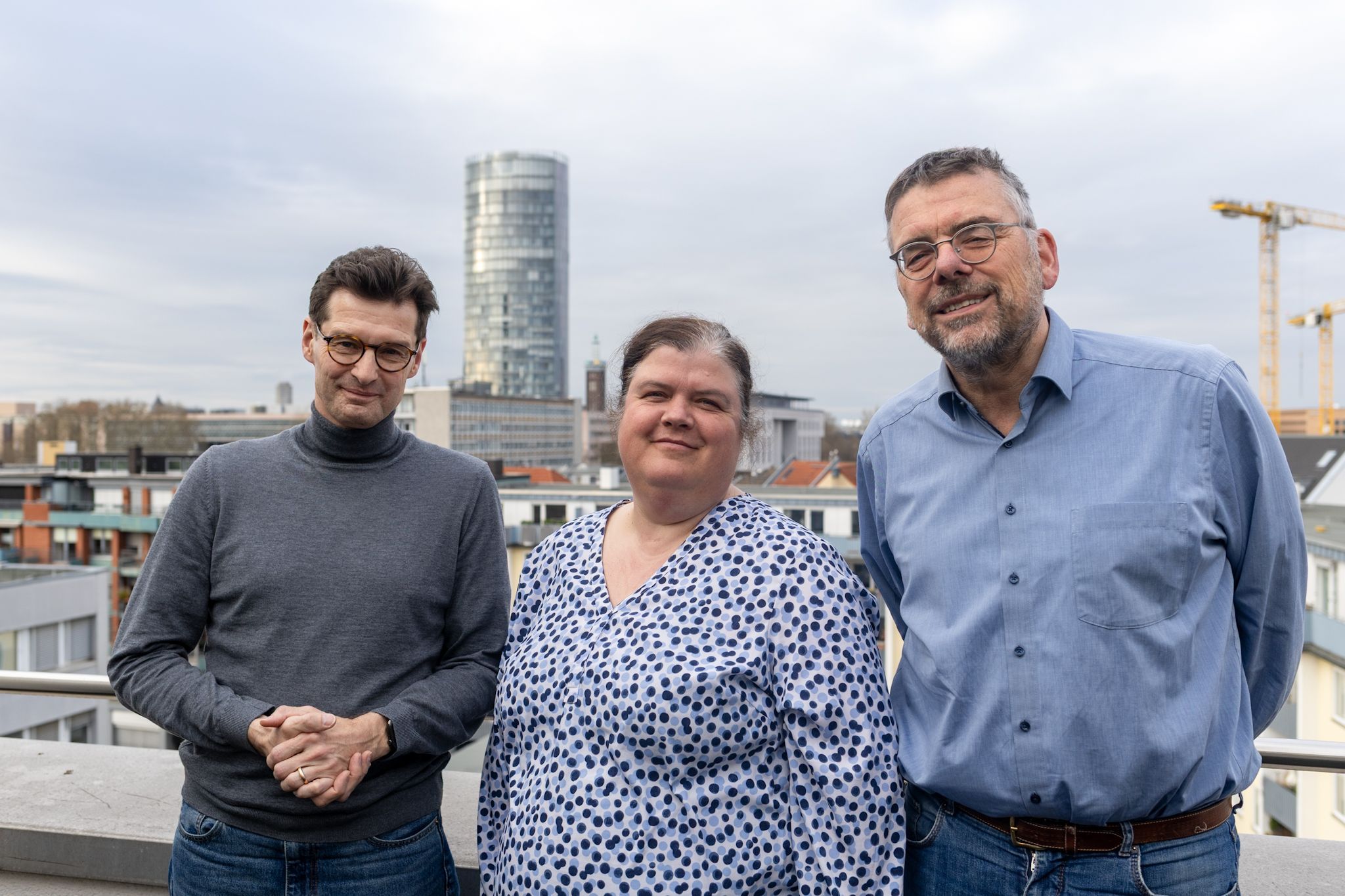 Zwei Männer und eine Frau in der Mitte schauen in die Kamera.
