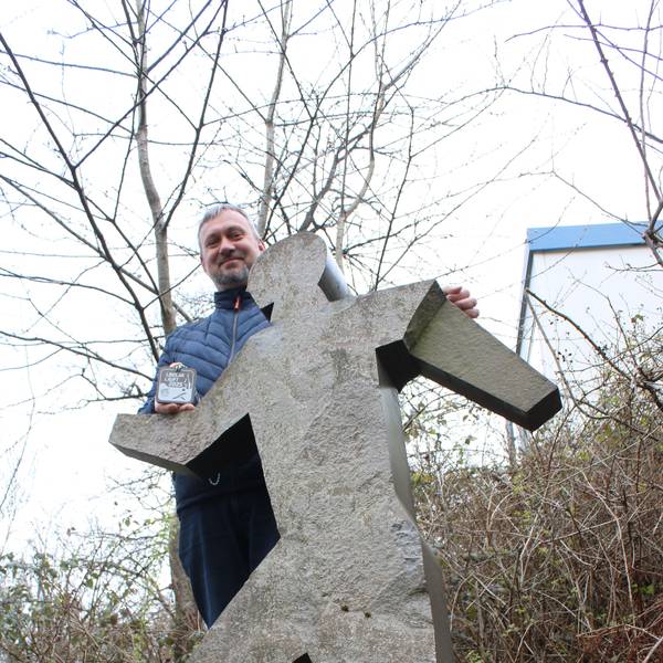 Ein Mann steht hinter einer Figur aus Grauwacke.