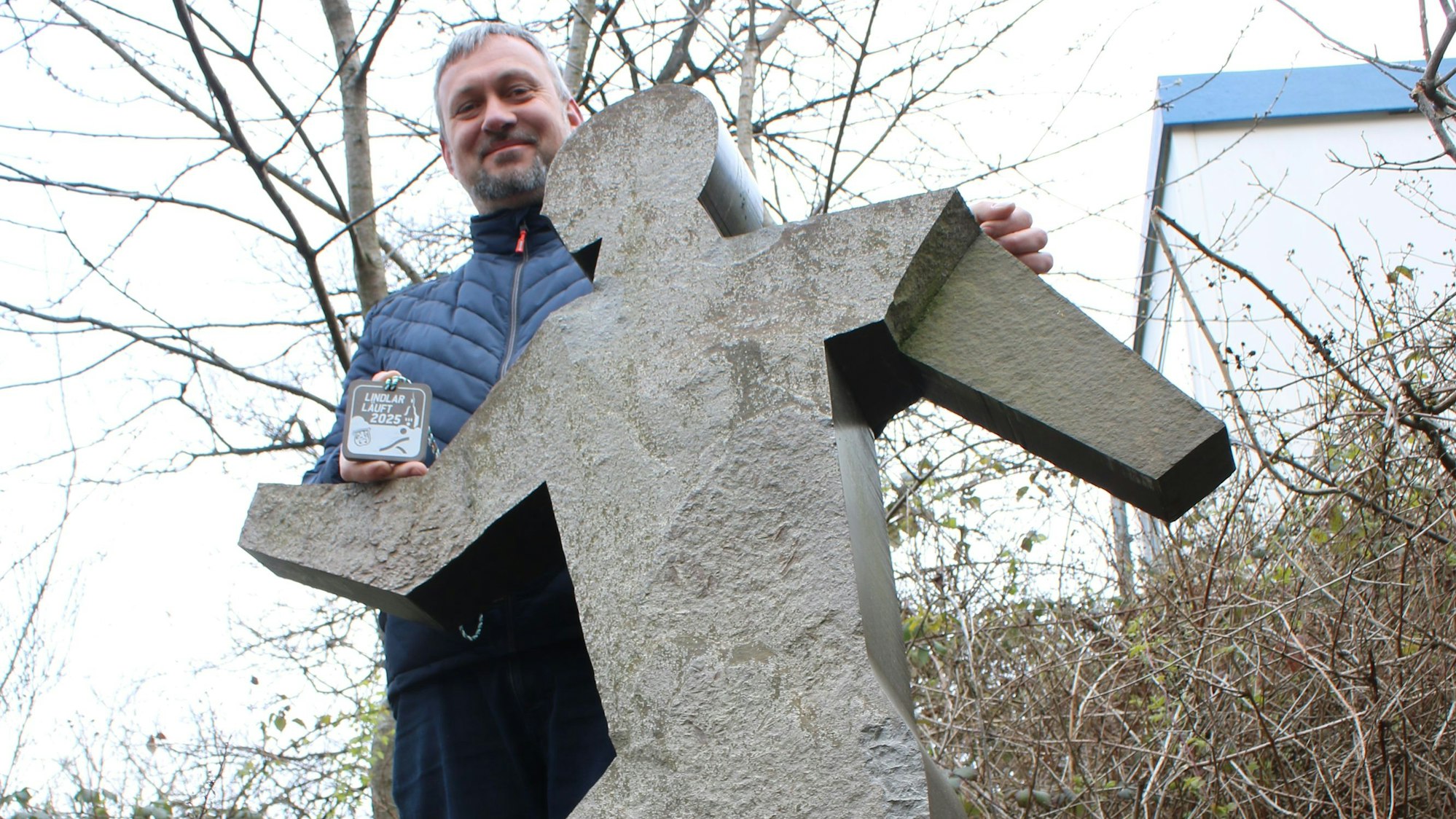 Ein Mann steht hinter einer Figur aus Grauwacke.