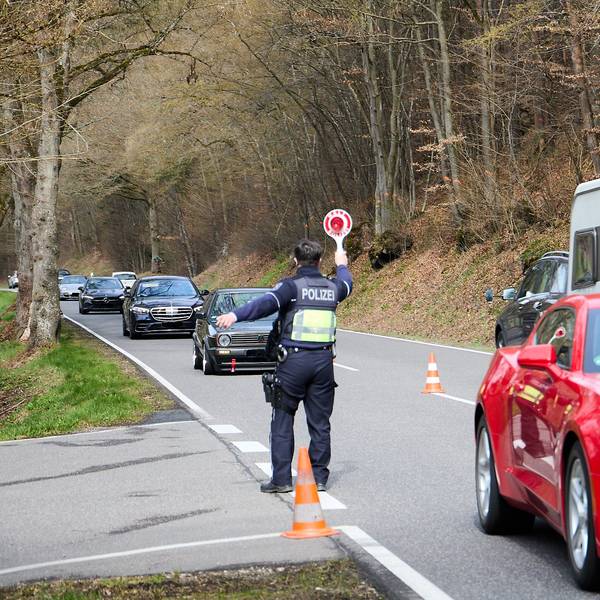 Ein Polizeibeamter winkt mit einer Kelle Autos auf einen Parkplatz.