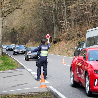 Ein Polizeibeamter winkt mit einer Kelle Autos auf einen Parkplatz.