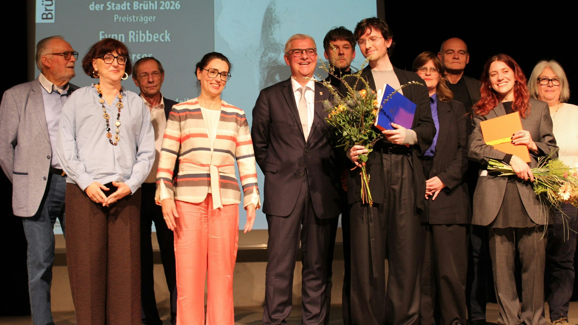 Menschen stehen auf einer Bühne.