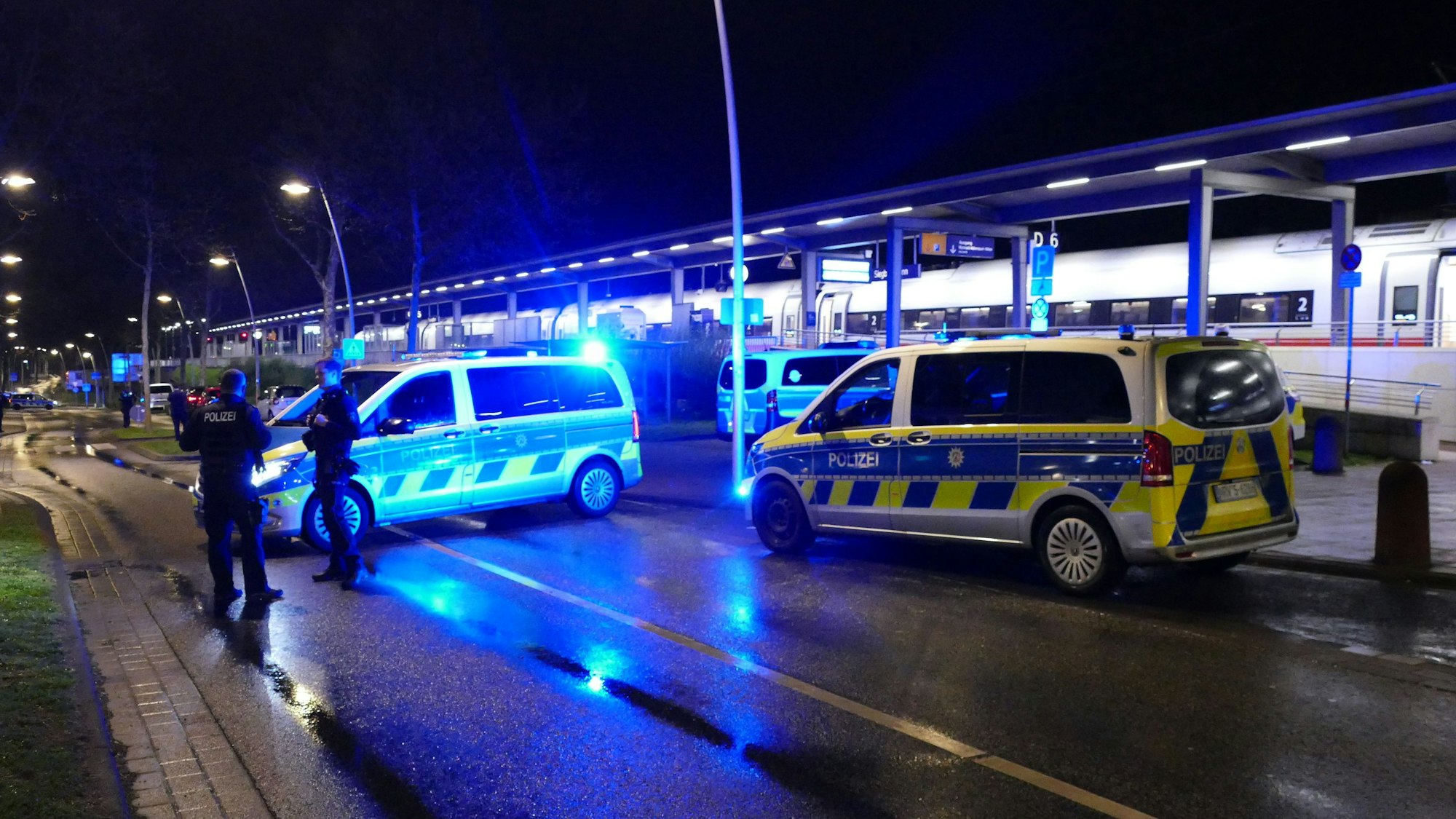 Mehrere Polizeifahrzeuge und Einsatzkräfte stehen am Siegburger ICE-Bahnhof.