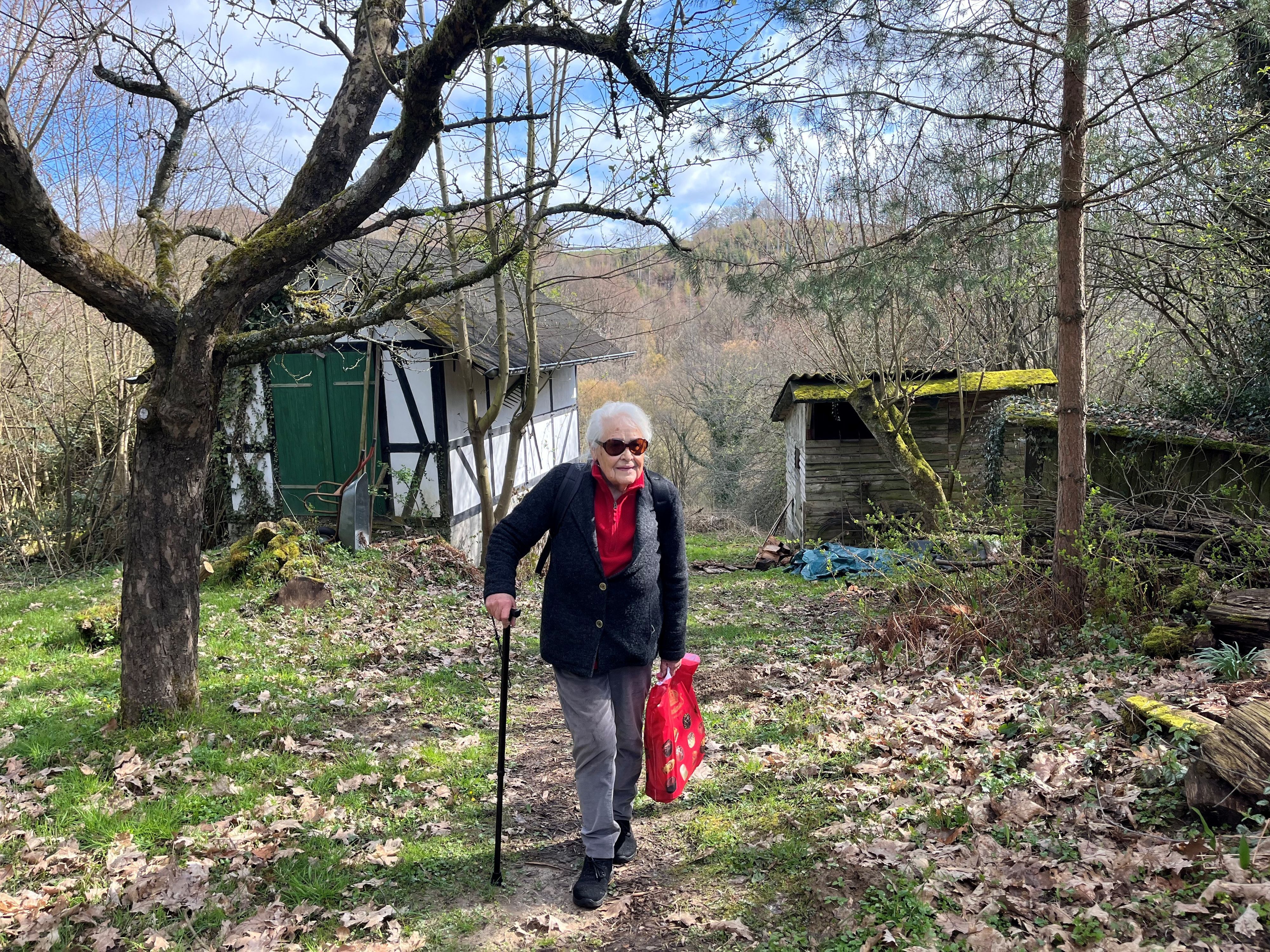 Die alte Dame stützt sich auf einen Stock.