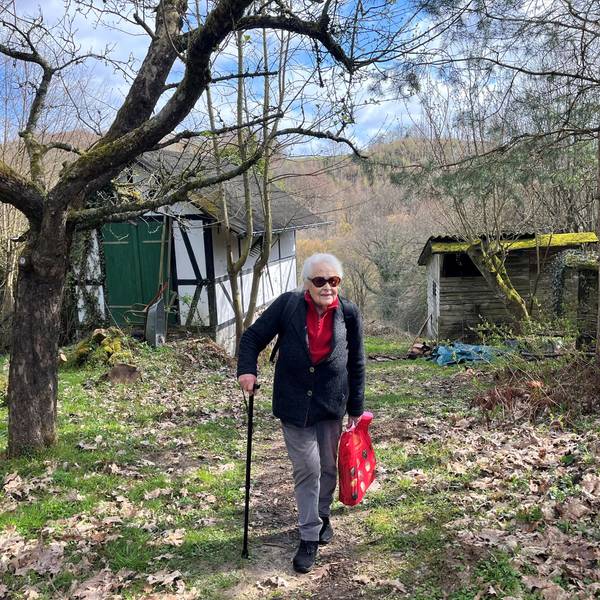 Die alte Dame stützt sich auf einen Stock.