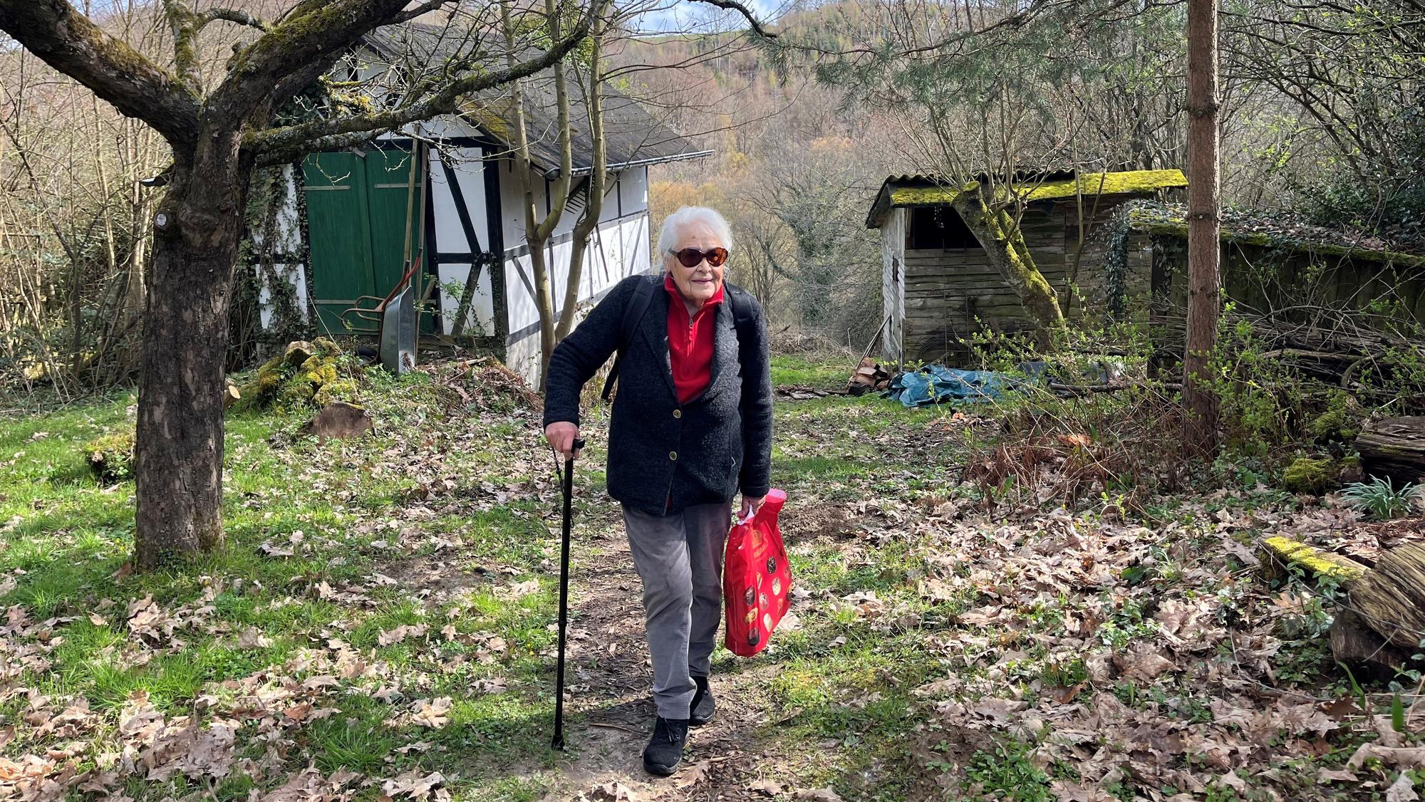 Die alte Dame stützt sich auf einen Stock.