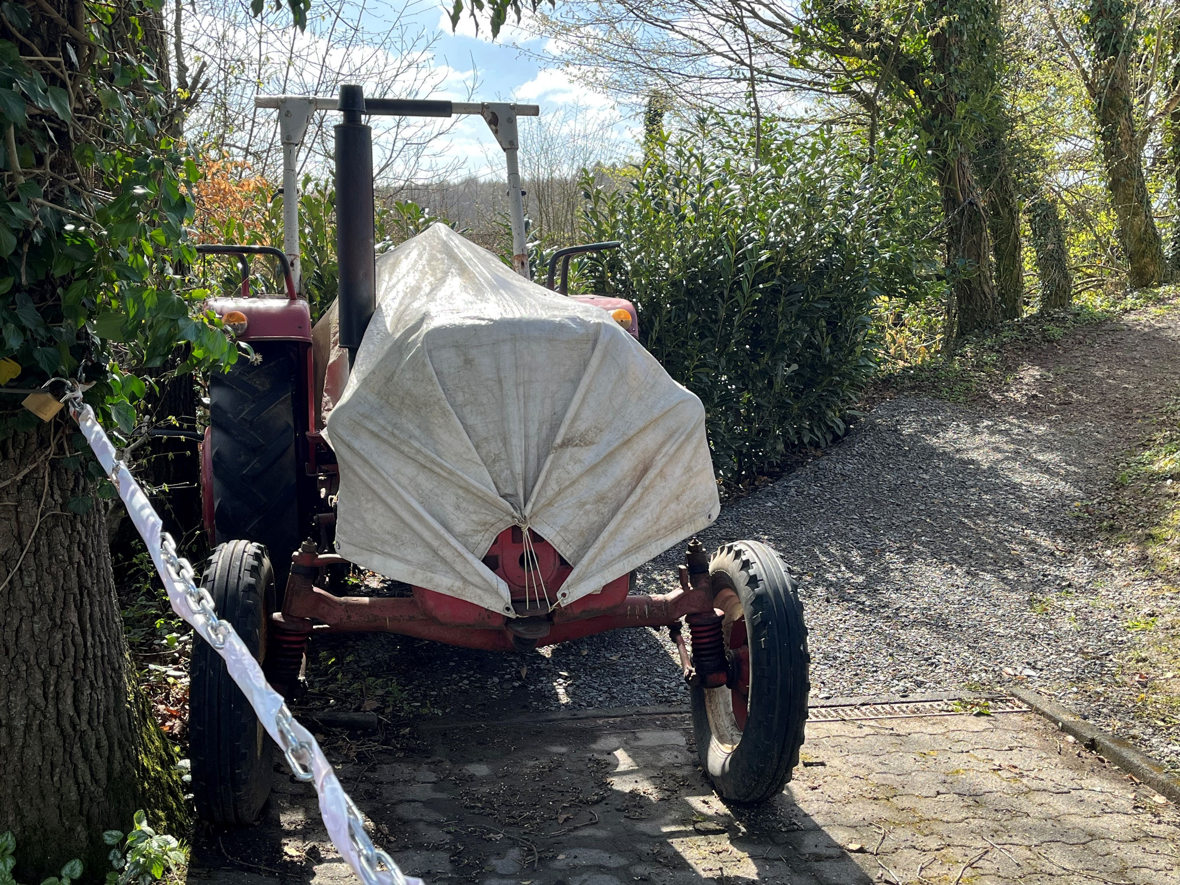 Im Vordergrund sind eine Kette und ein Traktor zu sehen, im Hintergrund die Bäume.
