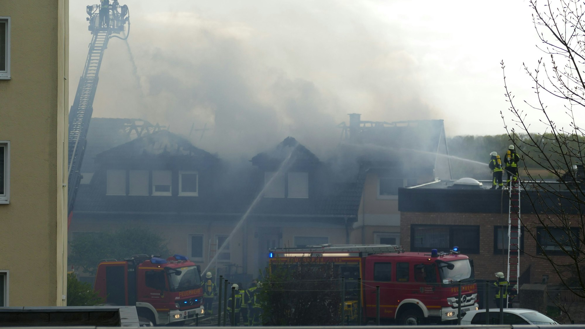 Viel Rauch kommt aus dem Dach eines brenenden Hauses. Die Feuerwehr versucht, zu löschen
