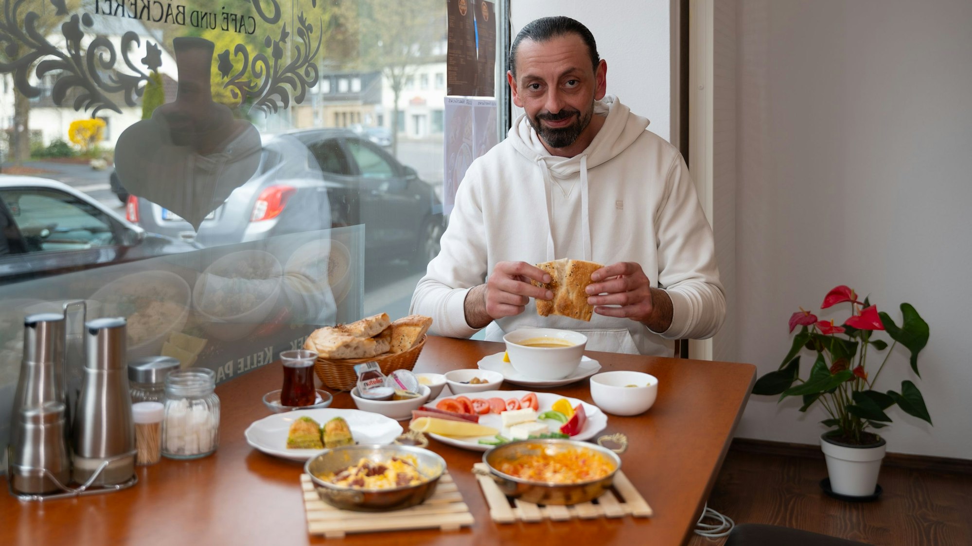 Erol Yildirim sitzt an einem gut gedeckten Frühstückstisch in seiner türkischen Bäckerei.
