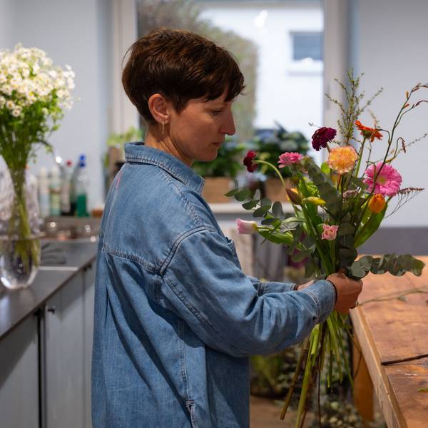 Eine Frau stellt einen Blumenstrauß zusammen.