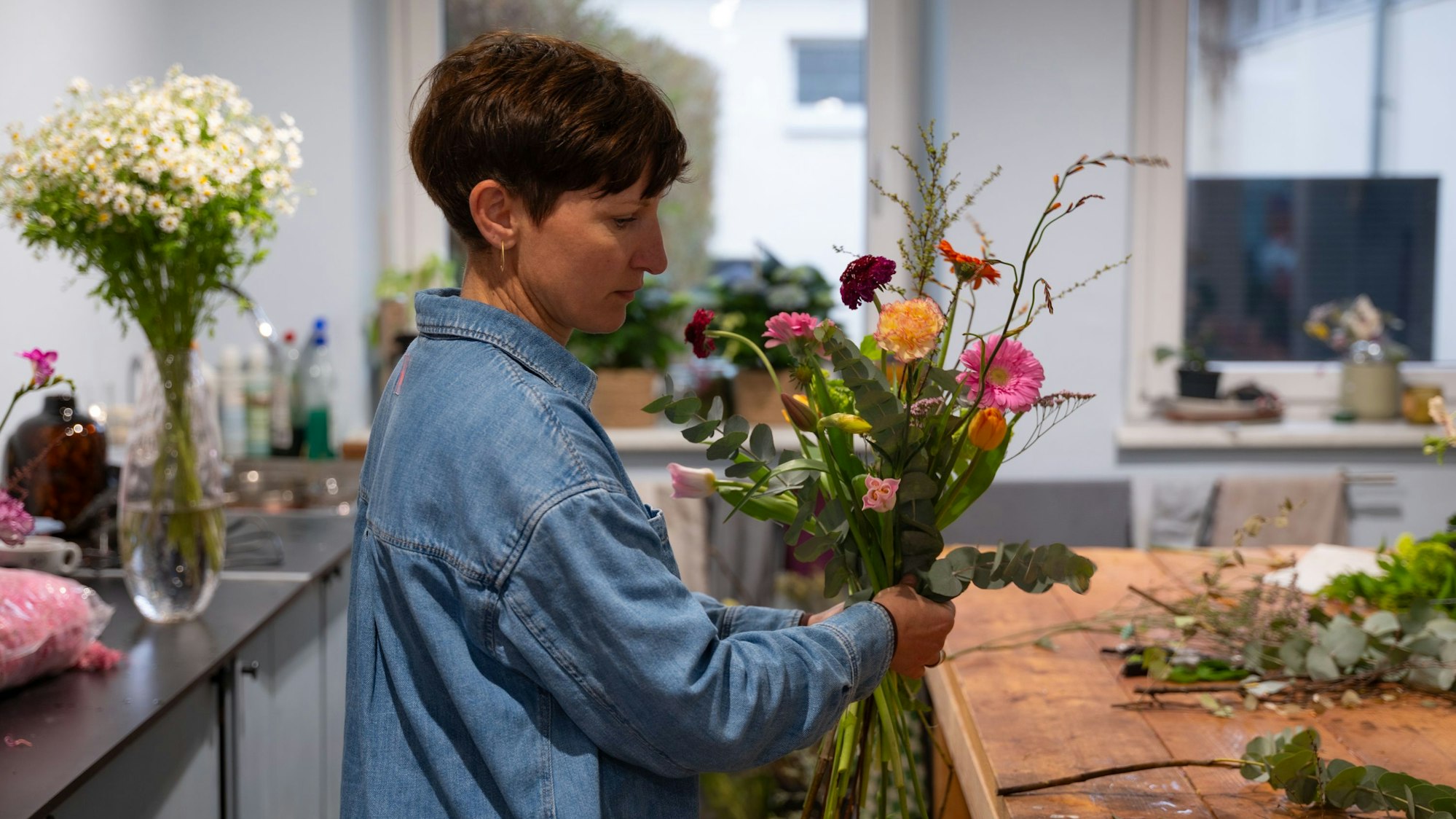 Eine Frau stellt einen Blumenstrauß zusammen.