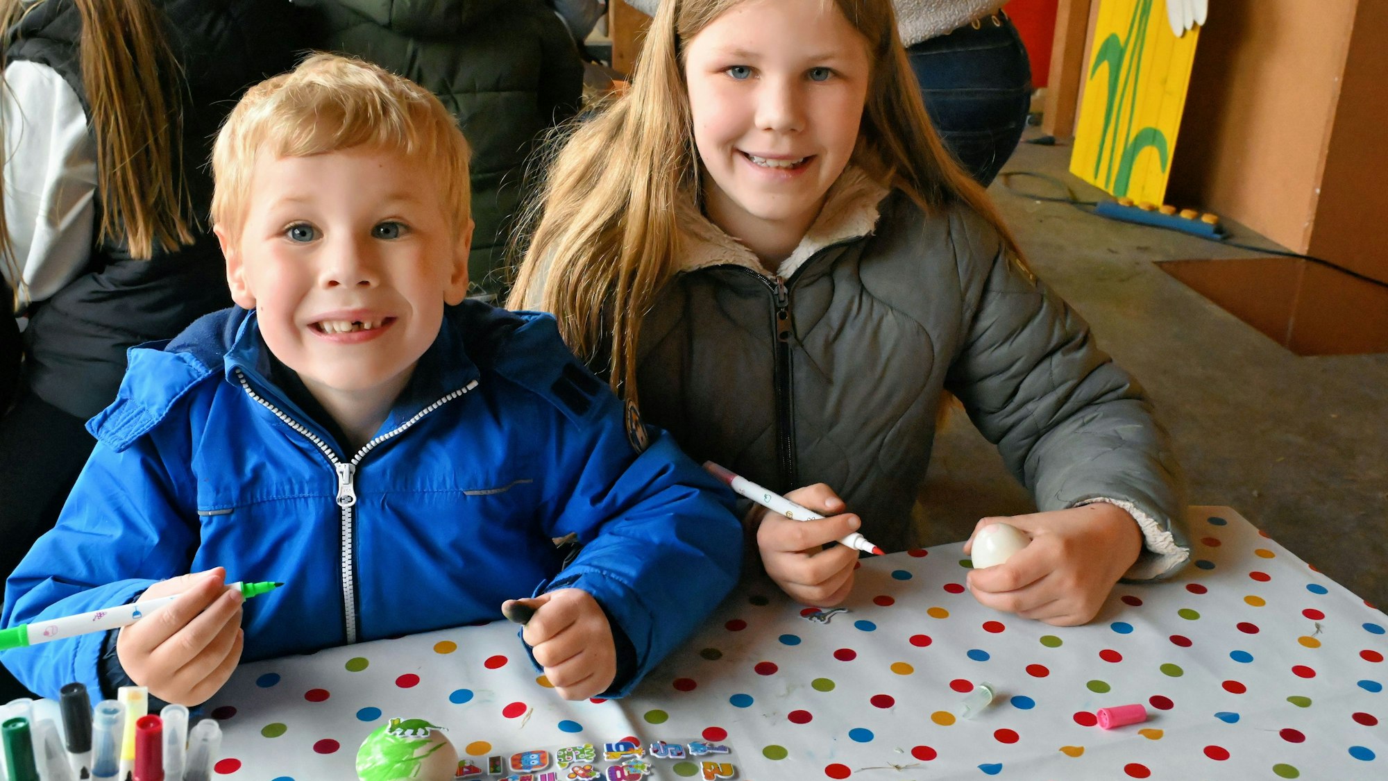 Die beiden Kinder bemalen ihre Ostereier.