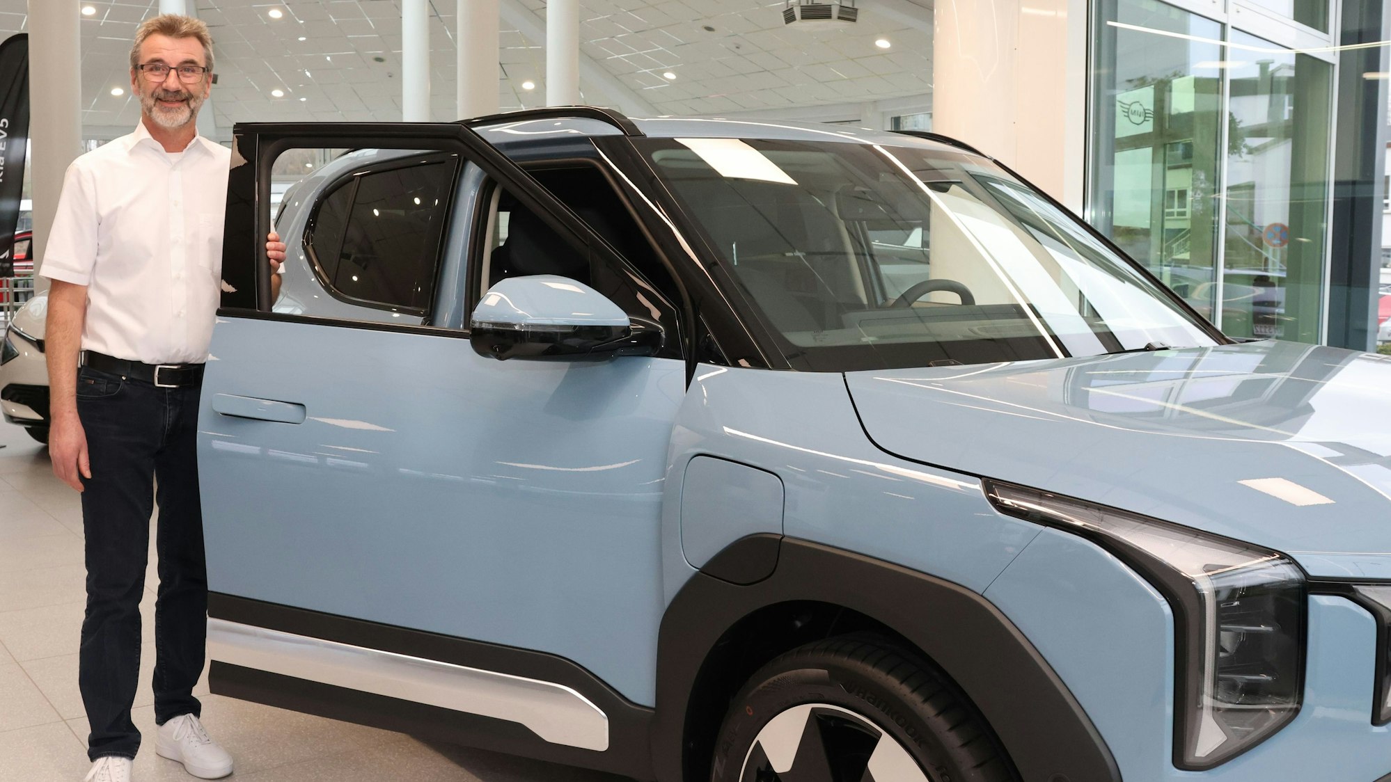 Bernd Ritter von Autohaus Kaltenbach in Wiehl-Bomig erklärt die Vorzüge von E-Autos und Hybriden, hier zeigt er einen Kia EV2.