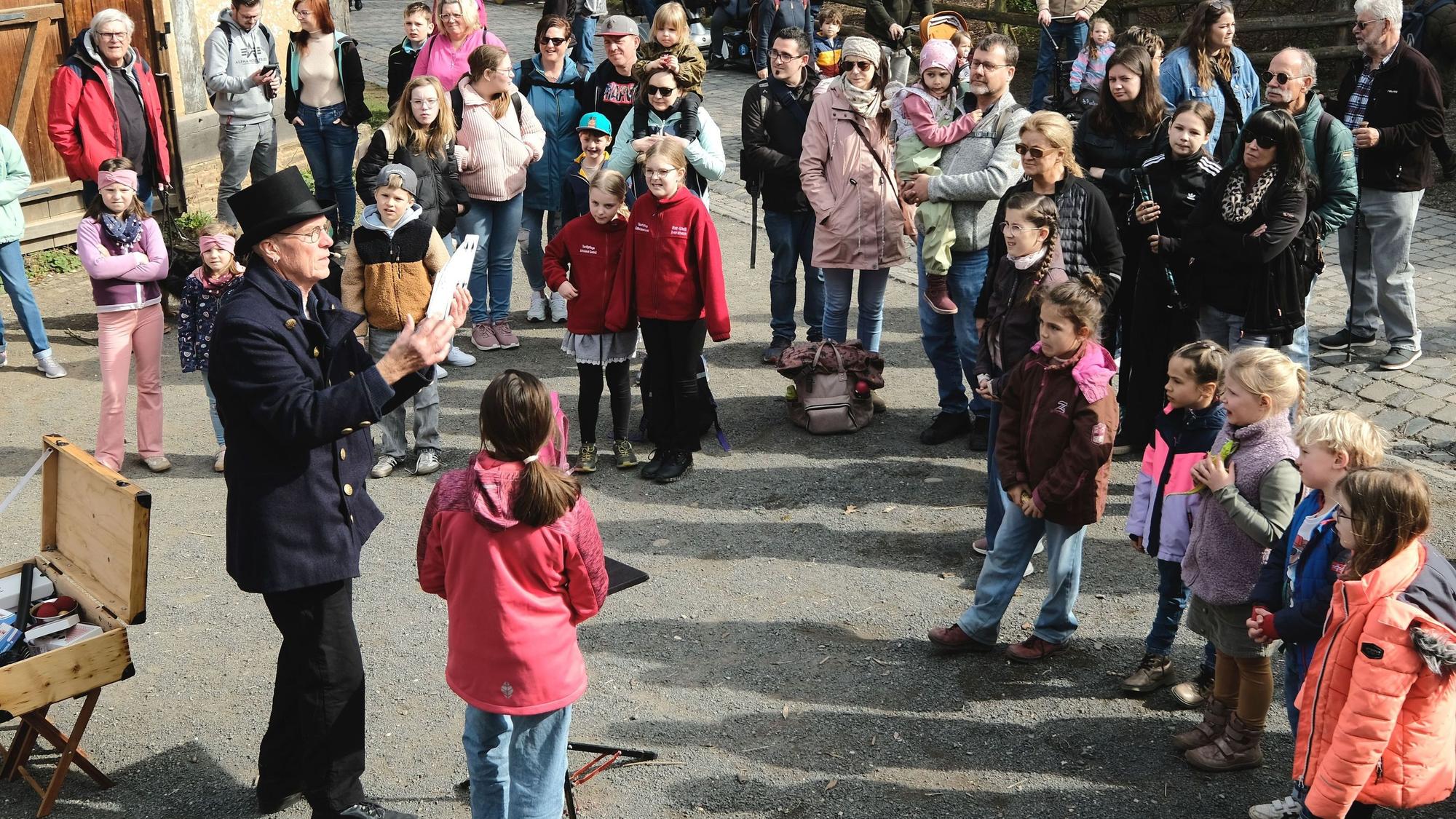 Beim Jahrmarkt anno dazumal stehen zahlreiche Besucher um den Zauberer herum.