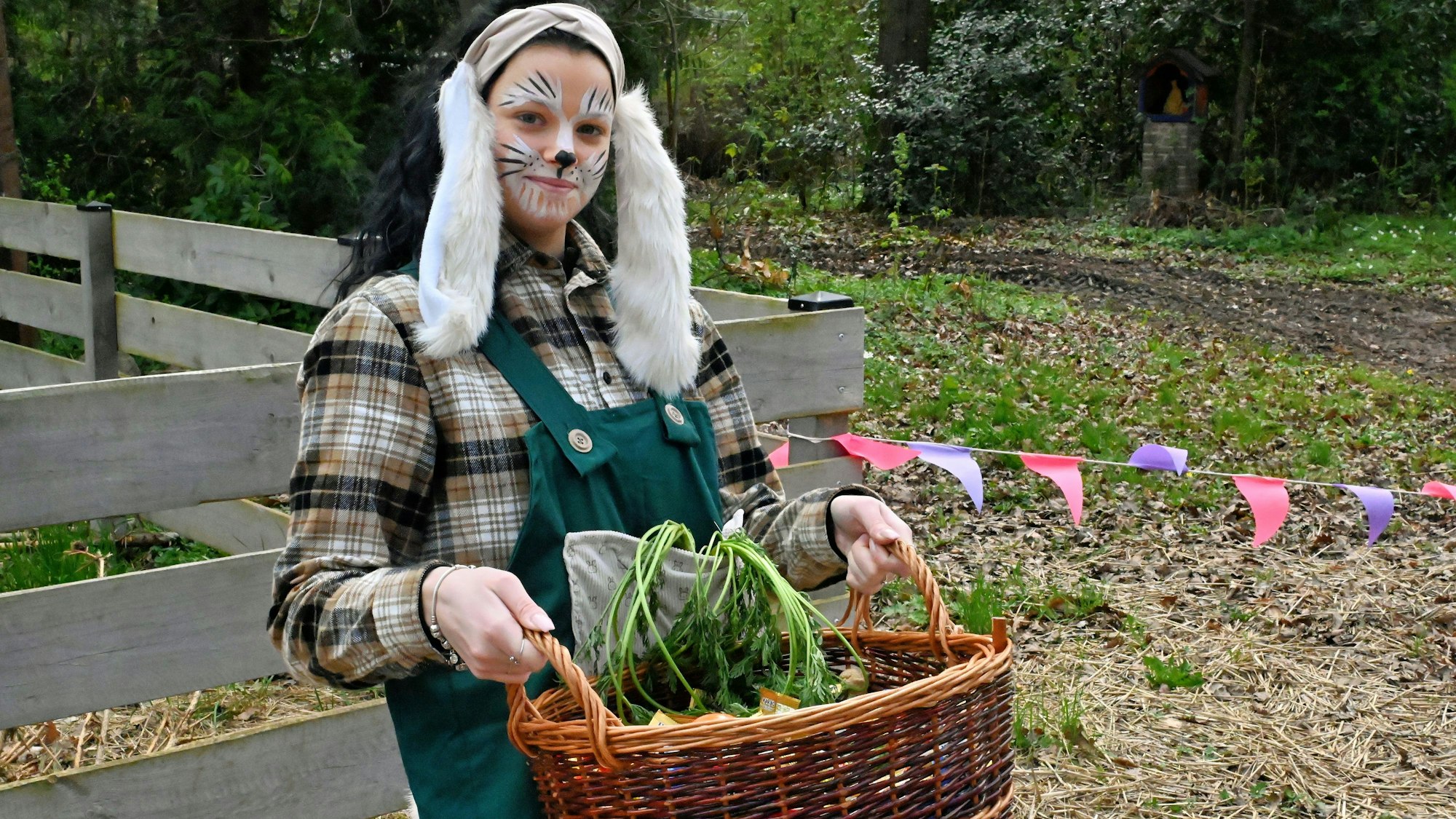 Eine junge, als Osterhase kostümierte Mitarbeiterin, schleppt in einem Weidenkorb weiteres Naschwerk heran.