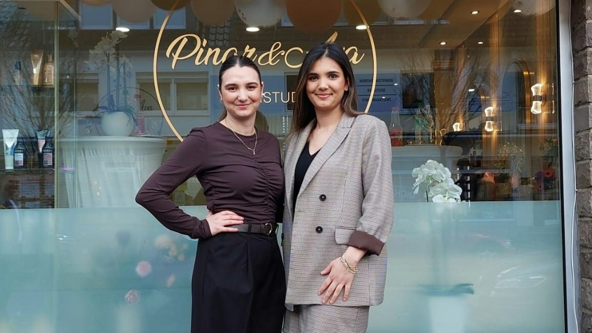 Zwei Schwestern stehen vor ihrem eigenen Friseursalon bei der Eröffnung.