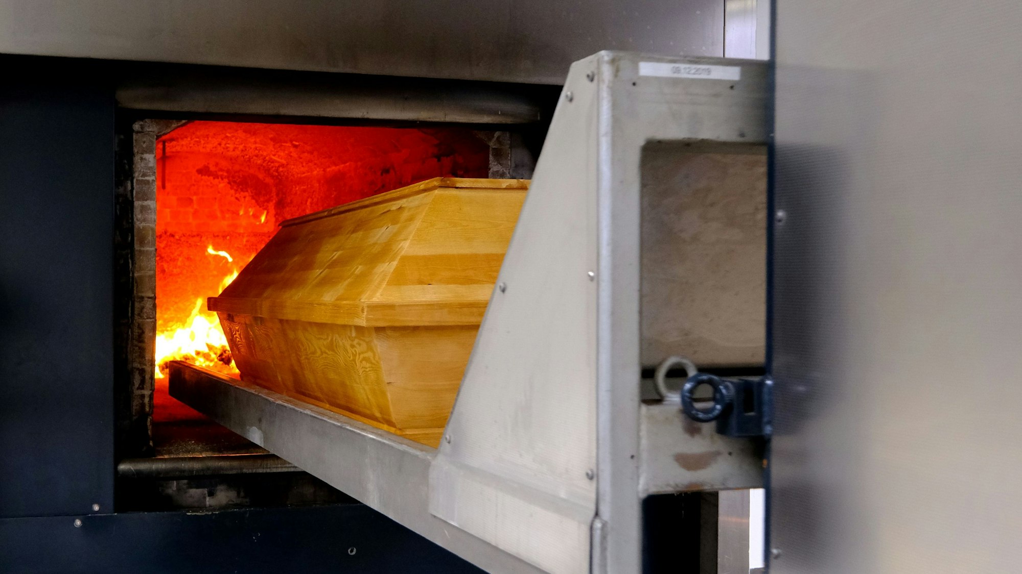 Der Sarg wird maschinell in die auf 800 Grad vorgeheizte Brennkammer geschoben.
