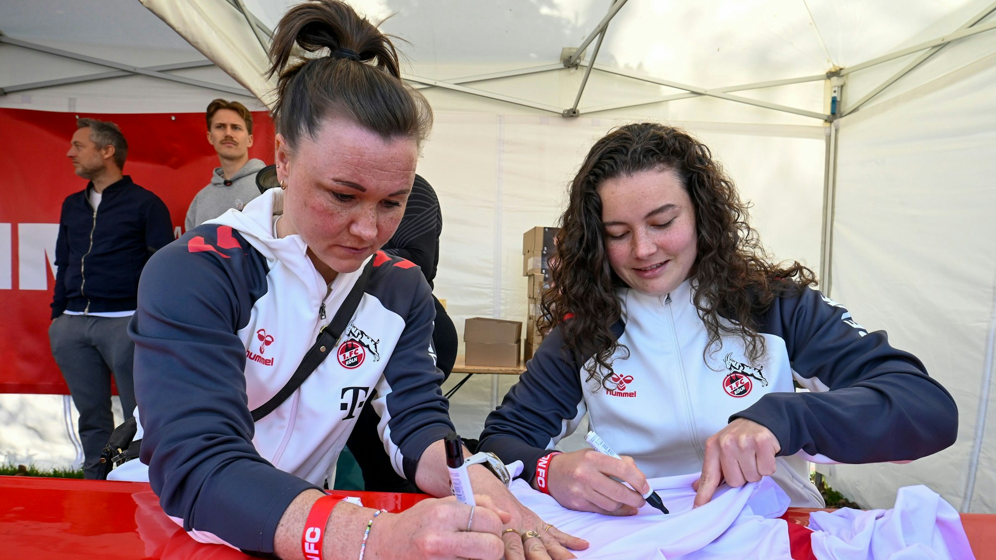 Die FC-Spielerinnen Marina Hegering und Amelie Bohnen geben Autogramme.