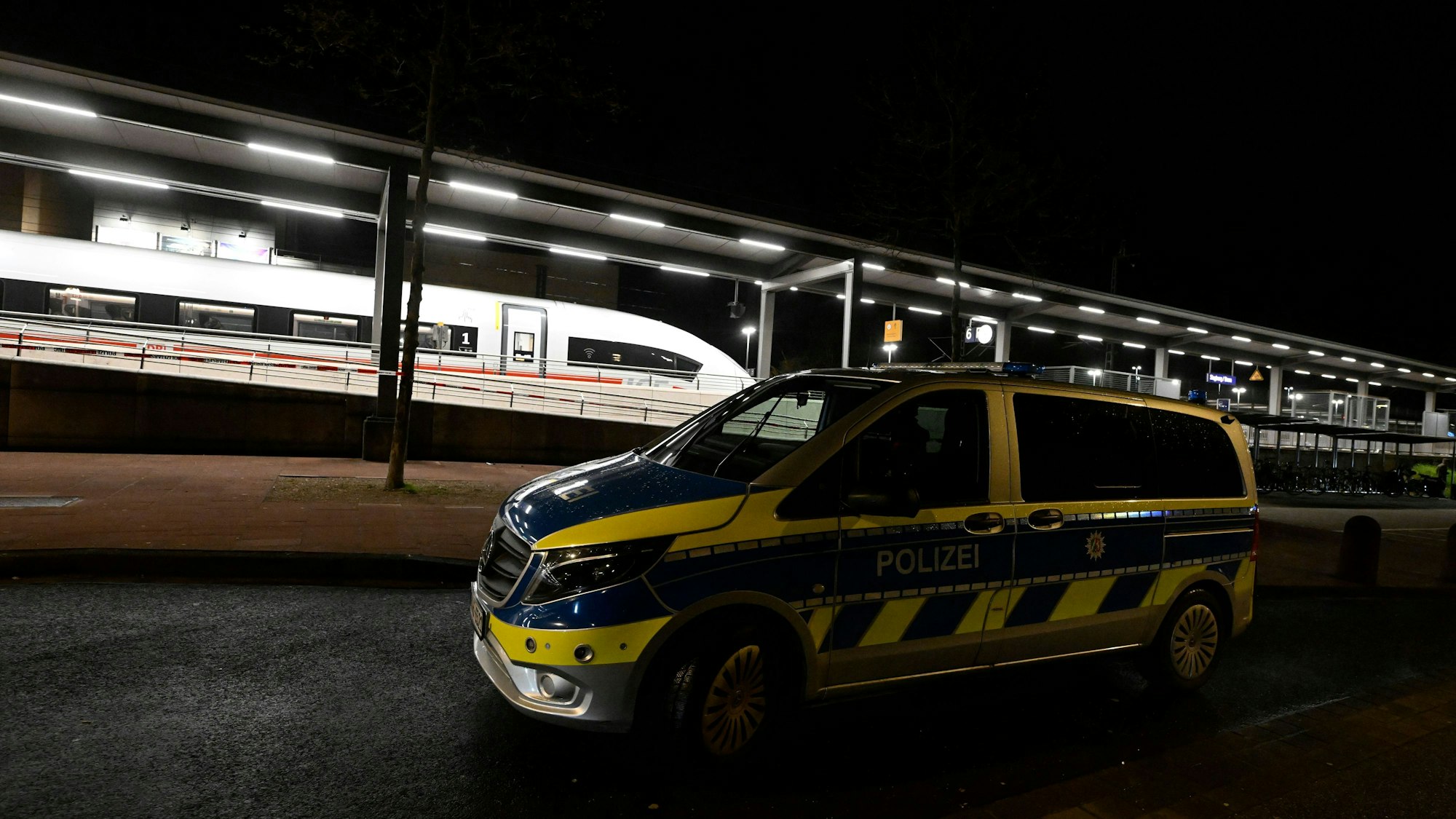 Ein Polizeifahrzeug steht vor einem Bahnsteig im Bahnhof Siegburg, auf dem ein ICE der Deutschen Bahn steht. Ein Mann hatte in einem ICE mit einem Anschlag gedroht und mehrere Menschen leicht verletzt. (Archivbild)