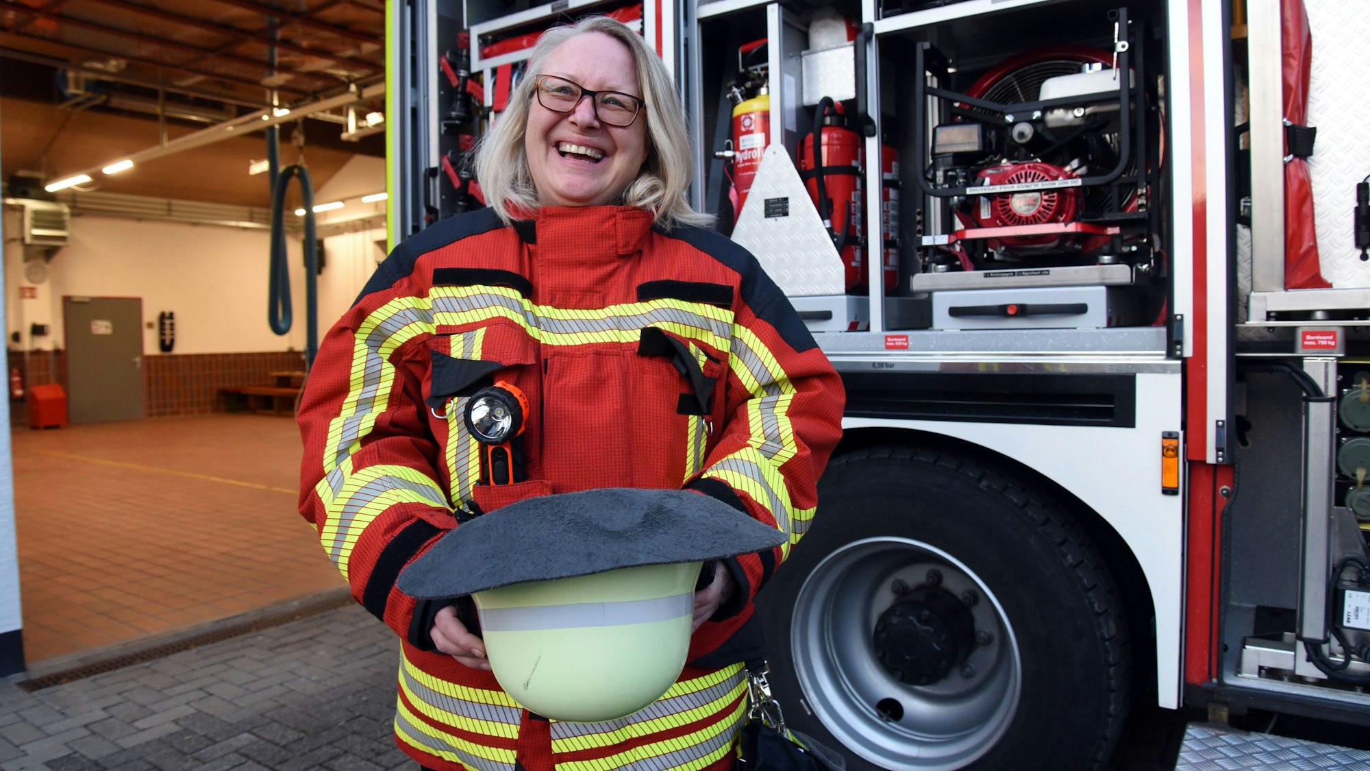Eine Feuerwehrfrau steht vor einem Feuerwehrauto.
