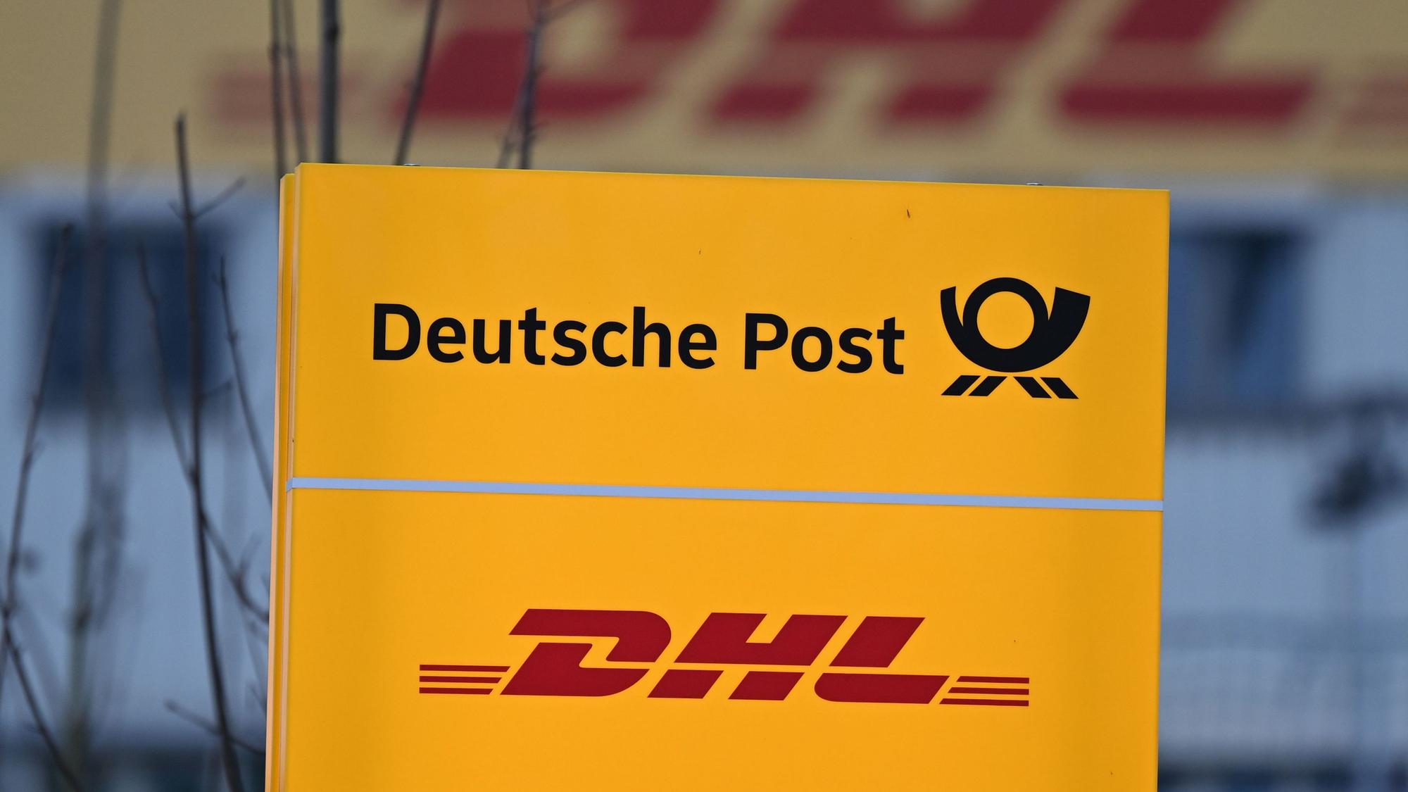 Die Logos DHL und Deutsche Post stehen vor dem DHL-Paketzentrum.