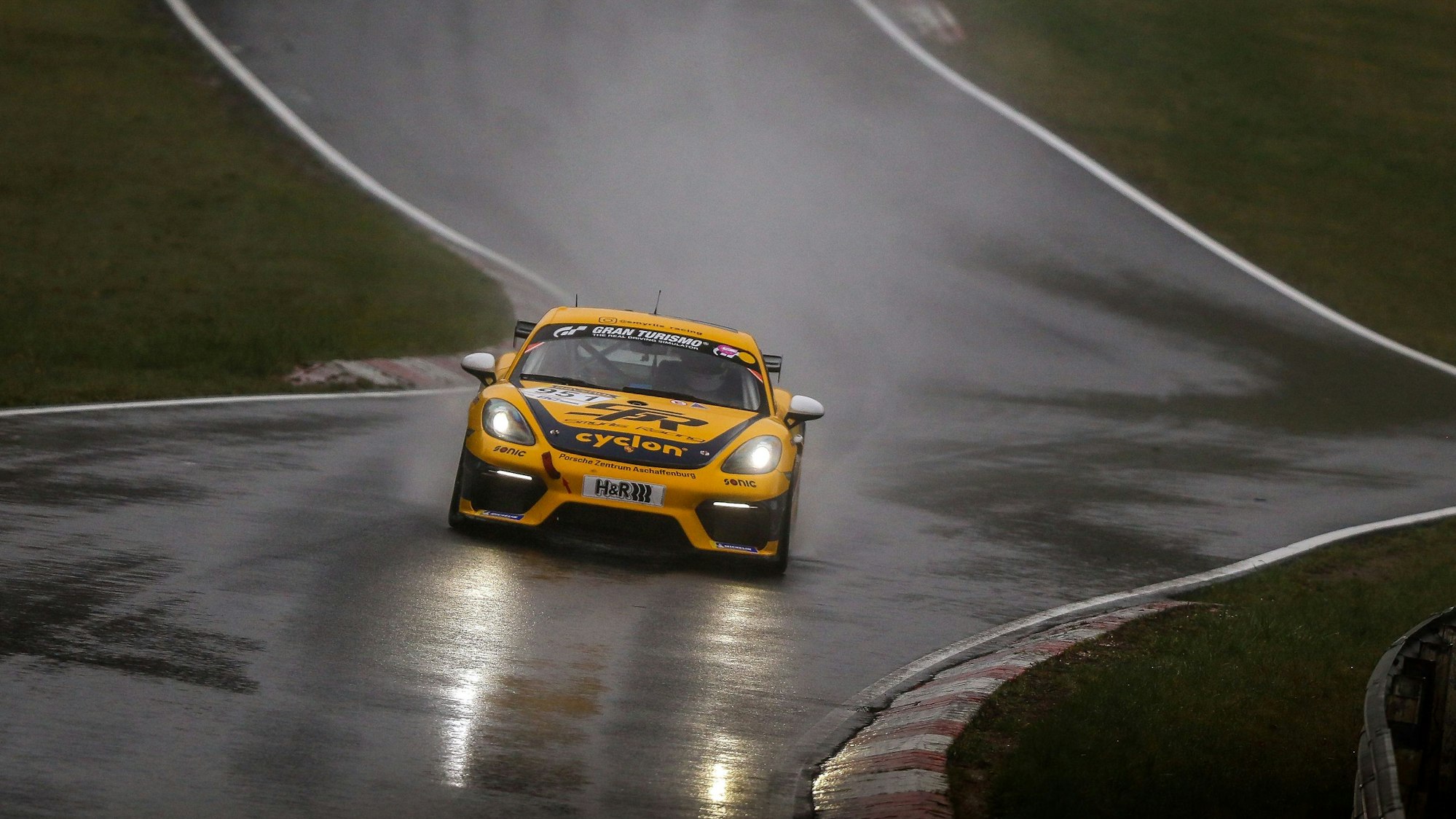 Das Foto zeigt einen Rennwagen auf regenasser Straße auf dem Nürburgring.