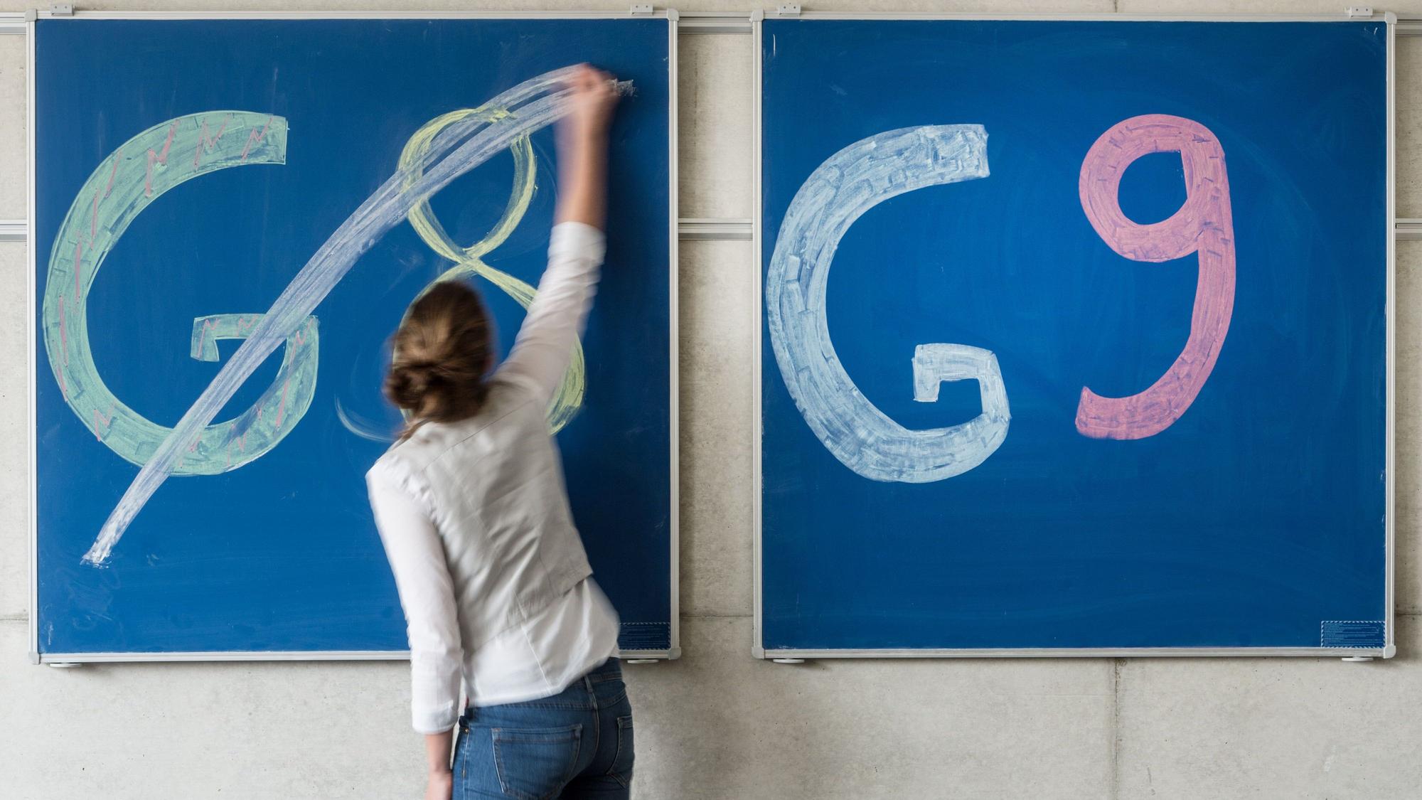 Eine Schülerin der streicht den Schriftzug «G8» an einer Tafel durch, daneben lässt sie «G9» unberührt.