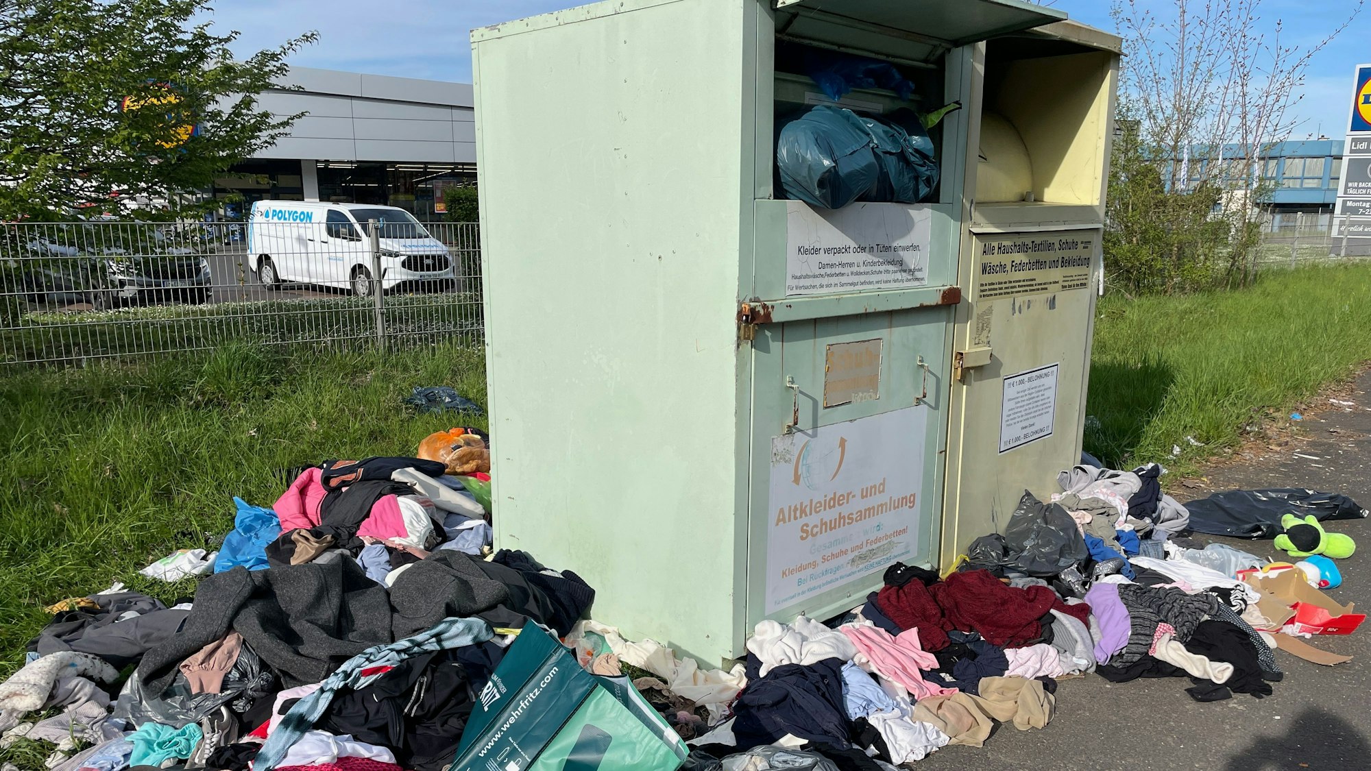 Zwei kommerzielle Altkleidercontainer im Hahnwald und Müllberge drumherum.