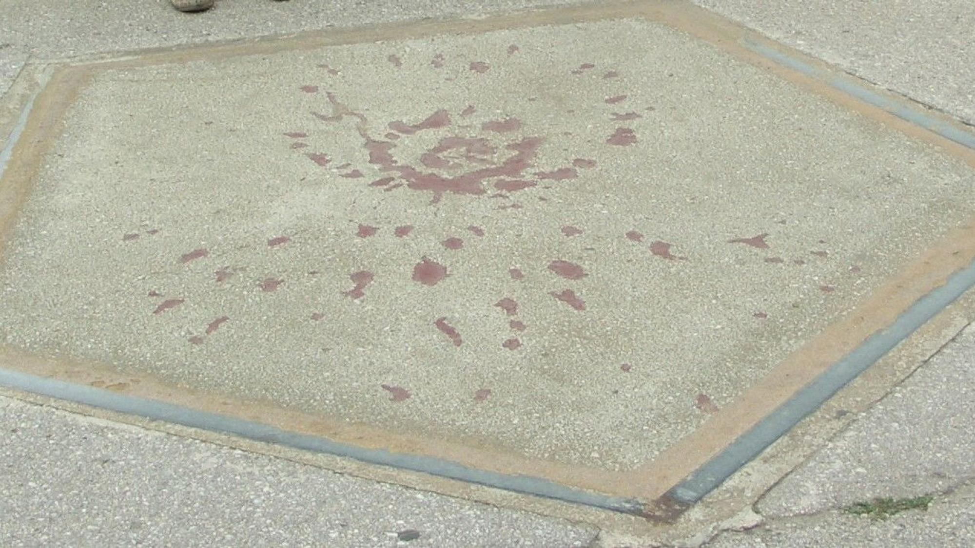 Ein grauer Asphalt, darauf rote Flecken.
