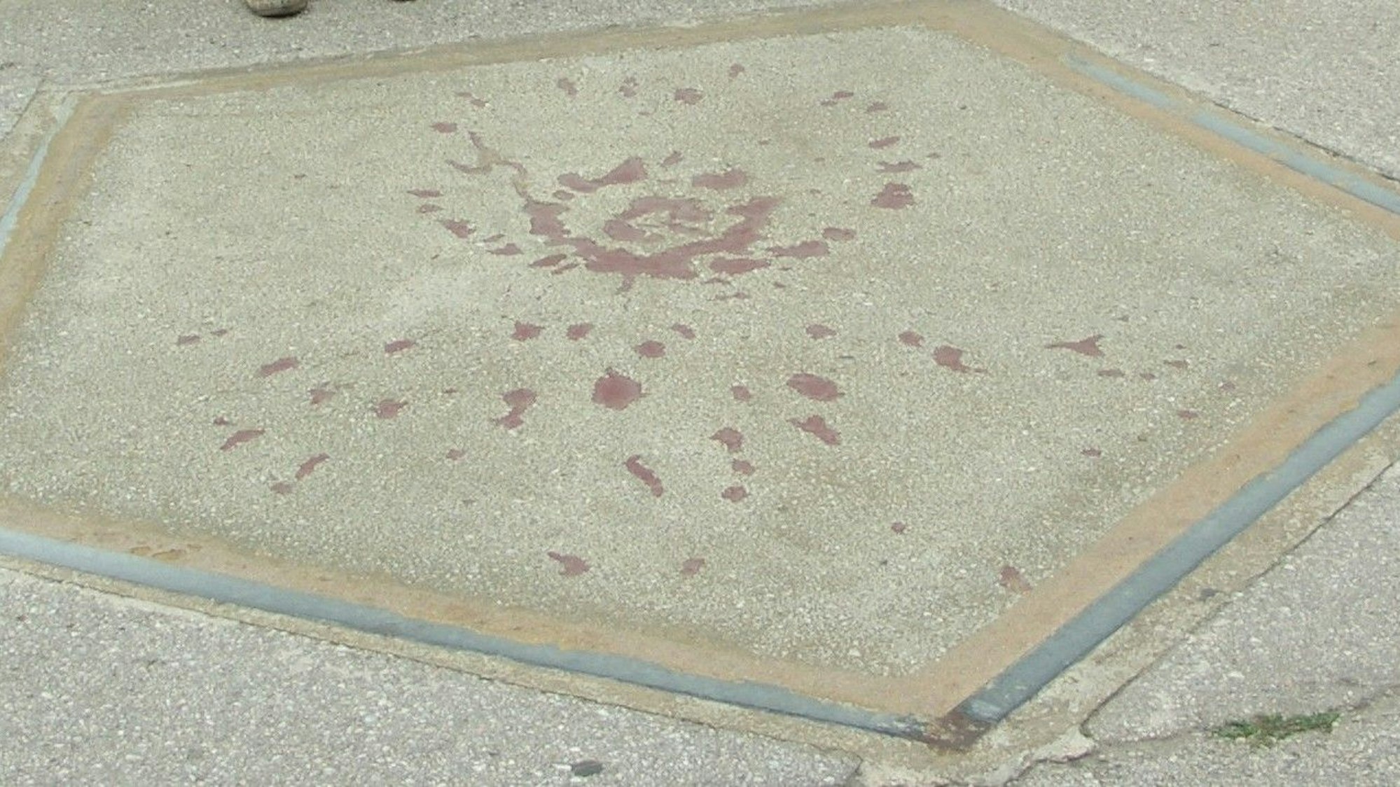 Ein grauer Asphalt, darauf rote Flecken.