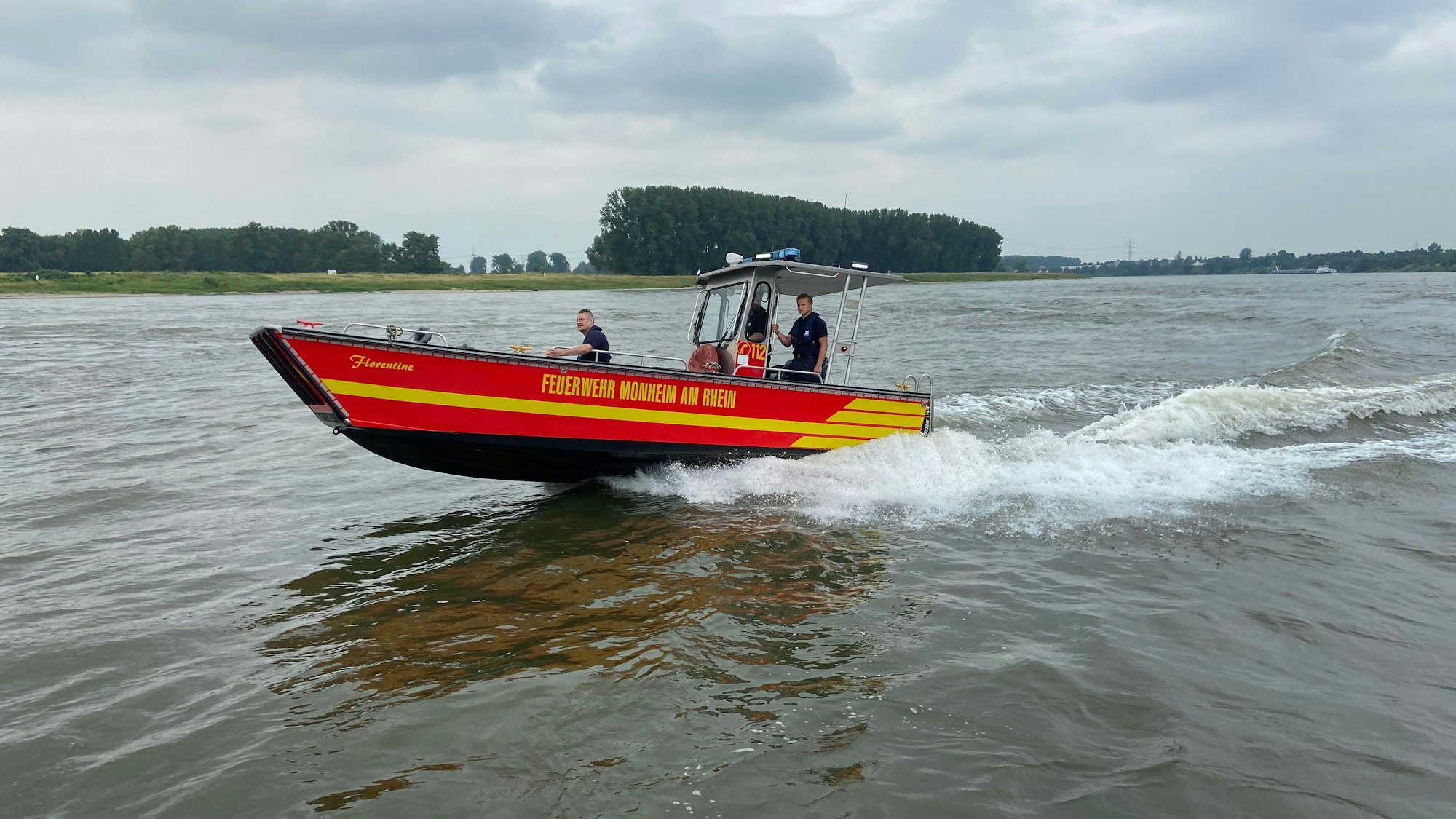 Einsatzkräfte der Feuerwehr auf dem Rhein bei Monheim im Einsatz.