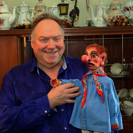 Zu sehen ist ein Mann mit einer Puppe.