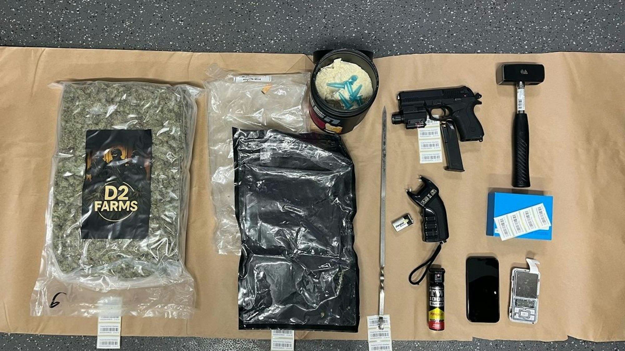 Sichergestellte Drogen, eine Waffe und weitere Gegenstände liegen auf einem Asservatentisch.