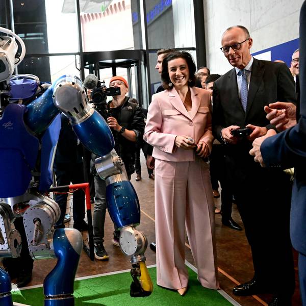 Das Foto zeigt Bundesforschungsministerin Dorothee Bär (Zweite von rechts= und Bundeskanzler Friedrich Merz (rechts) mit dem humanoiden Laufroboter Toro des Deutschen Zentrums für Luft- und Raumfahrt.