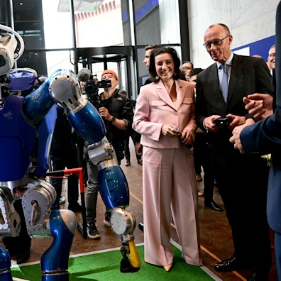 Das Foto zeigt Bundesforschungsministerin Dorothee Bär (Zweite von rechts= und Bundeskanzler Friedrich Merz (rechts) mit dem humanoiden Laufroboter Toro des Deutschen Zentrums für Luft- und Raumfahrt.