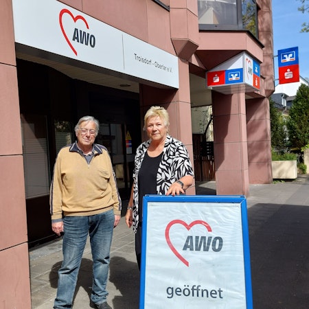 Udo Schumpe und Birgit Biegel stehen nebeneinander hinter einem Aufsteller, der auf das Awo-Zentrum hinweist.
