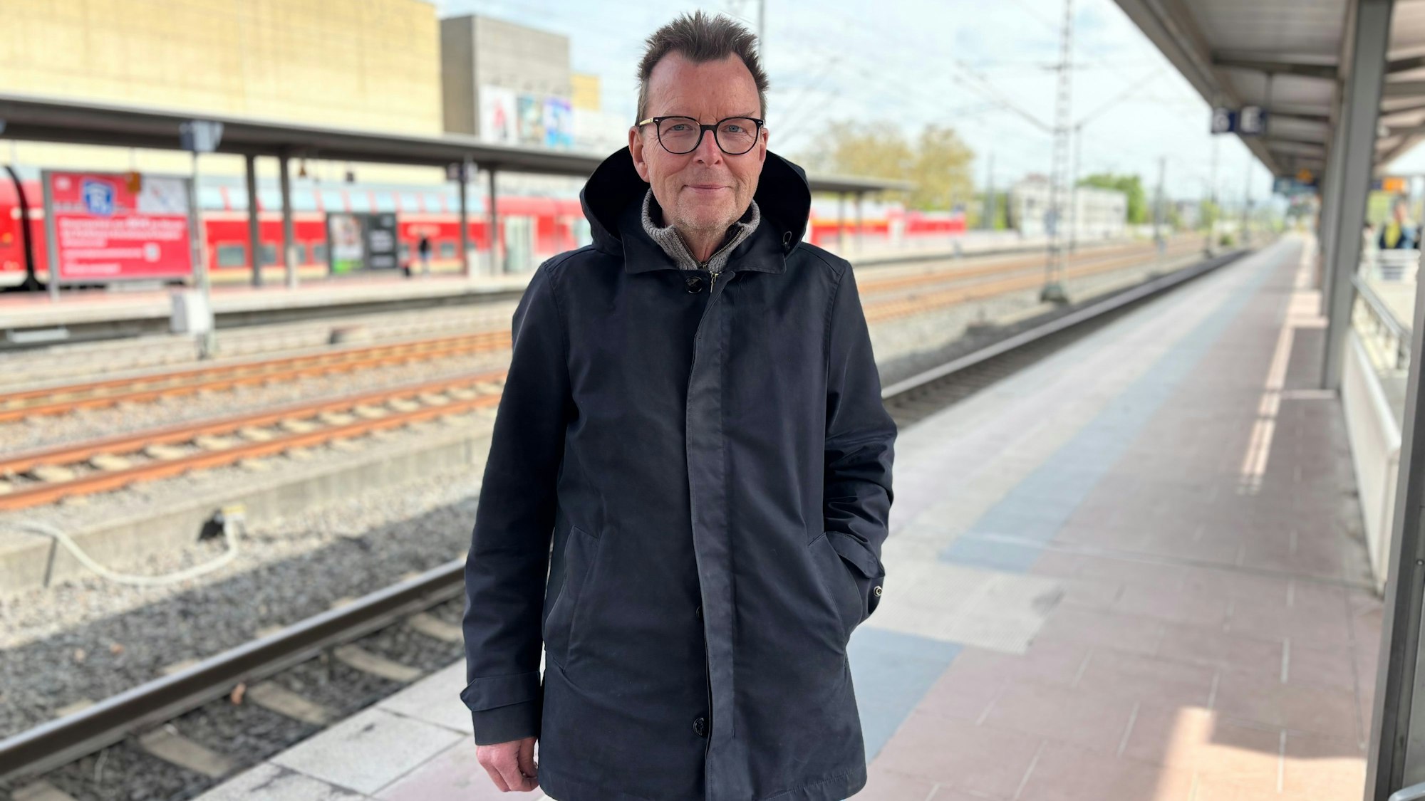 Peter Golzem steht am Siegburger Bahnhof. Im Hintergrund fährt ein Zug ein.