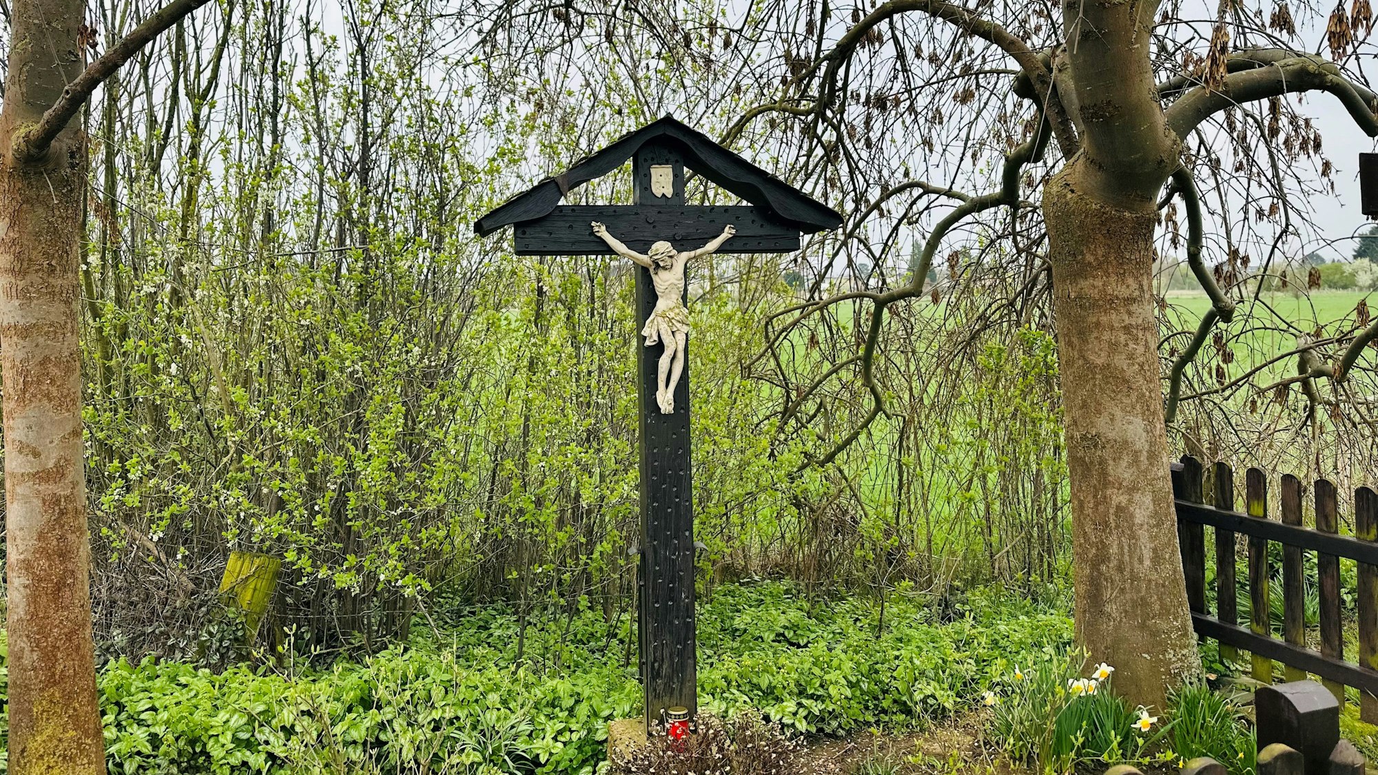 Das zeigt ein Wegekreuz unter Bäumen.