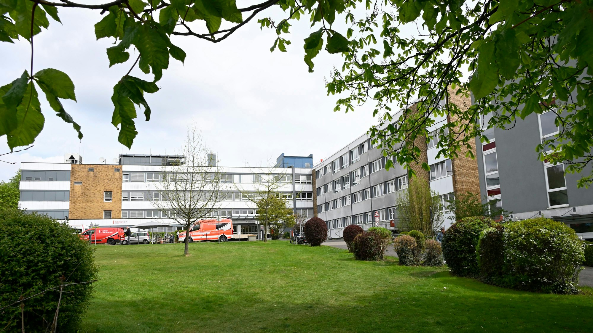 Ein graues Klinikgebäude, vorne ein grüner Rasen