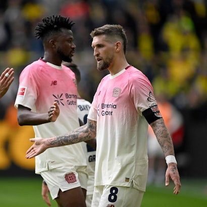 Bayer Leverkusen's German midfielder #08 Robert Andrich (R) is congratulated by Bayer Leverkusen's Argentinian midfielder #25 Exequiel Palacios (L) after scoring the 0-1 opening goal during the German first division Bundesliga football match between Borussia Dortmund and Bayer Leverkusen in Dortmund, western Germany, on April 11, 2026. (Photo by INA FASSBENDER / AFP) / DFL REGULATIONS PROHIBIT ANY USE OF PHOTOGRAPHS AS IMAGE SEQUENCES AND/OR QUASI-VIDEO