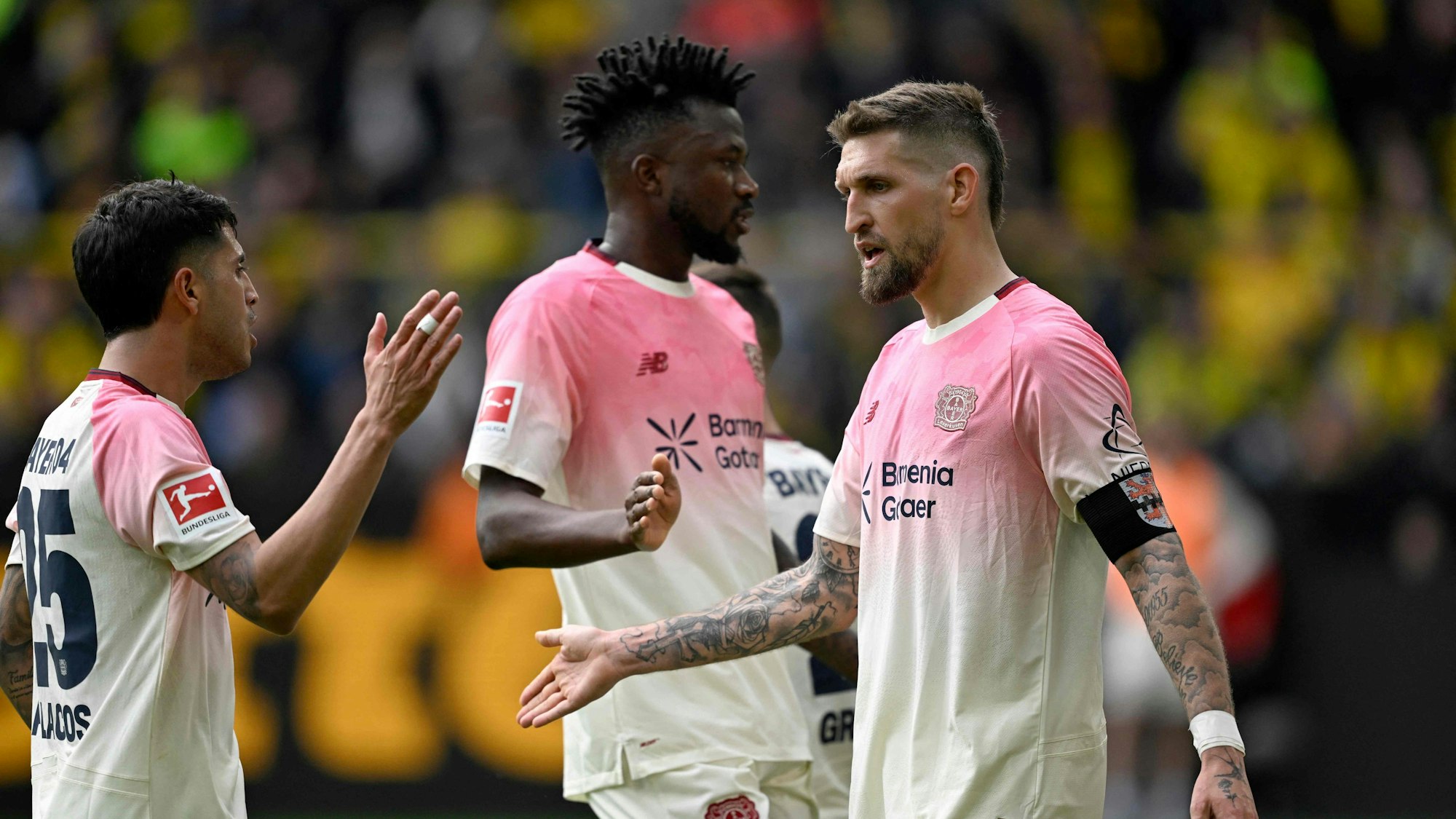 Bayer Leverkusen's German midfielder #08 Robert Andrich (R) is congratulated by Bayer Leverkusen's Argentinian midfielder #25 Exequiel Palacios (L) after scoring the 0-1 opening goal during the German first division Bundesliga football match between Borussia Dortmund and Bayer Leverkusen in Dortmund, western Germany, on April 11, 2026. (Photo by INA FASSBENDER / AFP) / DFL REGULATIONS PROHIBIT ANY USE OF PHOTOGRAPHS AS IMAGE SEQUENCES AND/OR QUASI-VIDEO